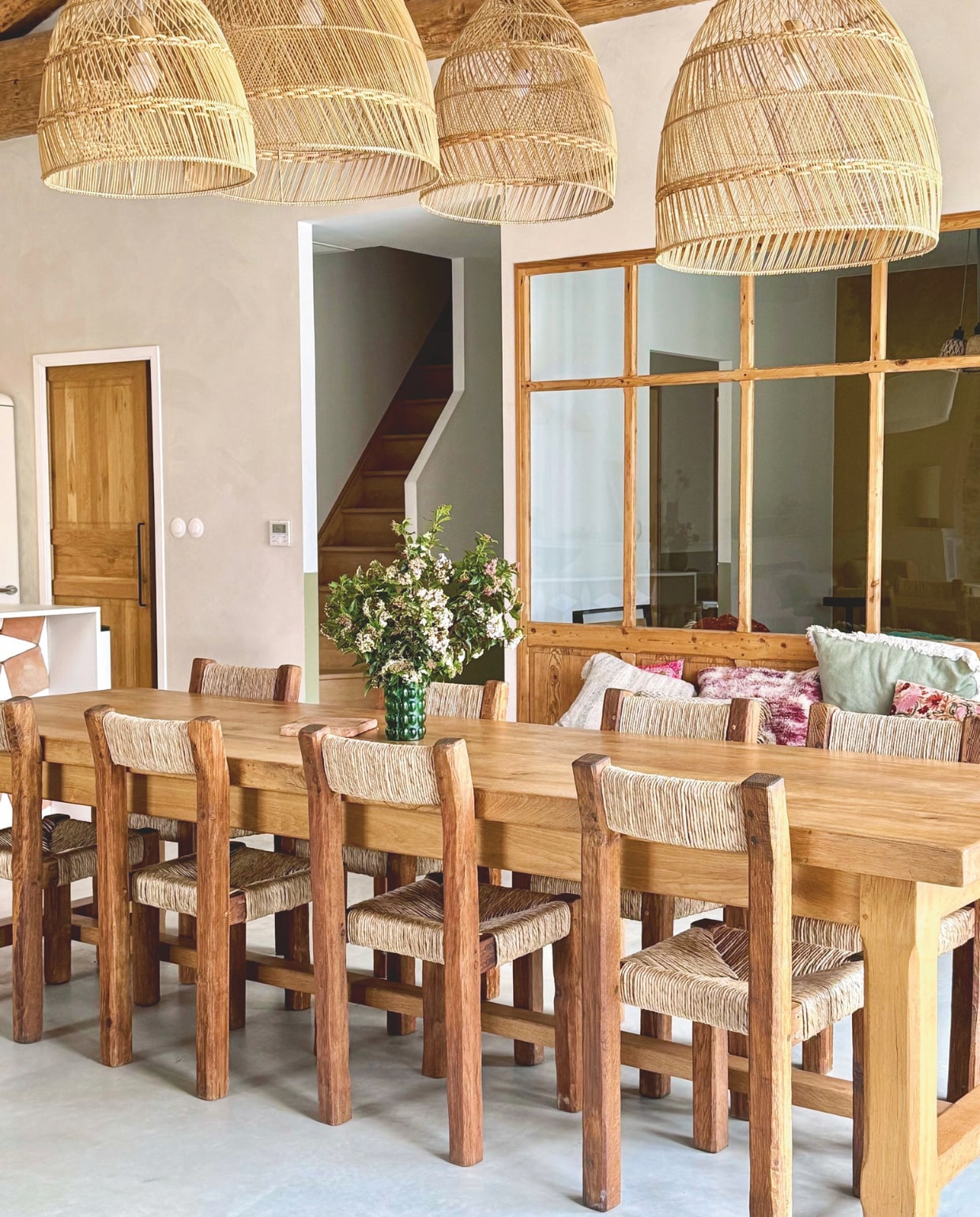Stoelen in brutalisme-stijl geweven door Arnaud, tafel kringloop. Rotan hanglampen My Bohem, vaas La Belle Vie. Vloer gepolijst beton, muren geschilderd met kalkverf van Mercadier in kleur Boumian. vtwonen 07-2025 | fotografie Manon Ferra