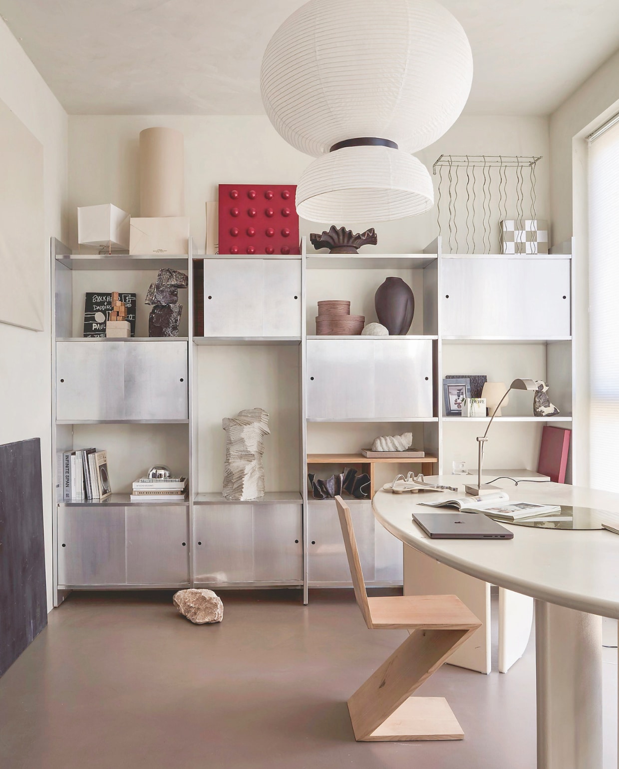 Kast Ikea. Werktafel zelfgemaakt. Hanglamp Formakami van &Tradition. Tafellamp Paper Cube van Hay. Vaas Sumo Slim van 101 Copenhagen. Ovale houten dozen Mango. Wanddecoratie Stone Metallic/Holo Kwantum. Plisségordijnen Energy in Marshmallow van Veneta. Zigzagstoel in naturel essen van Gerrit Rietveld. Muurverf Fresco in Casa Blanca van Pure & Original. Grijze en zwarte steensculpturen in kast, schilderijen tegen muur zelfgemaakt. vtwonen DIY-special | fotografie Peggy Jansen