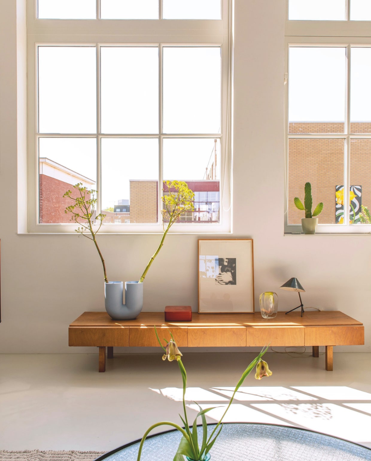 Vintage dressoir. Vaas Kink van Muuto. Japanse bentobox vintage. Kunstwerk van Patrick Merckaert. Glazen vaas Floris Meydam. Lamp Pinocchio van H. Busquet voor Hala. stijlvol wonen 7-2025 | styling Anke Helmich | fotografie Caroline Coehorst