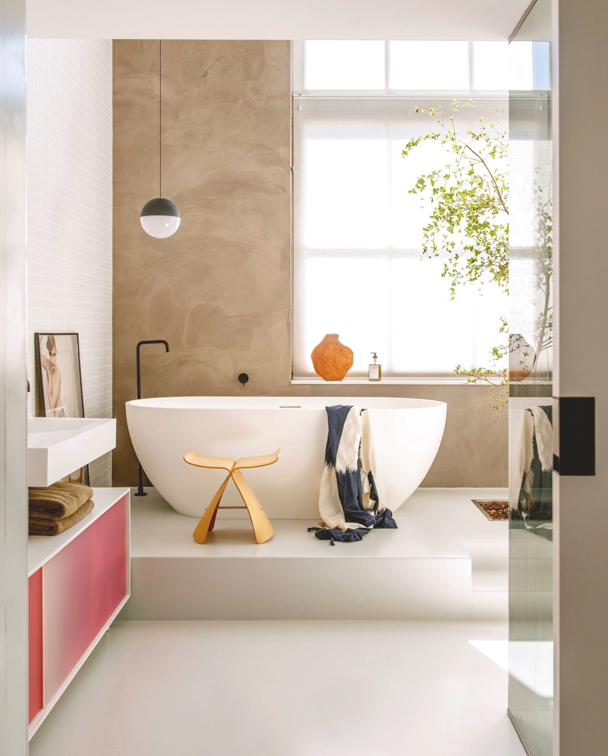 Butterfly Stool van Sori Yanagi van Vitra. Dressoir Shift van Scholten & Baijings voor Pastoe.  Hanglamp String Light Sphere van Michael Anastassiades voor Flos. Vaas Willem van Hooff. Bad Solid Surface via X2O. Wandtegels Villeroy & Boch. Boom Bucida buceras. stijlvol wonen 7-2025 | styling Anke Helmich | fotografie Caroline Coehorst