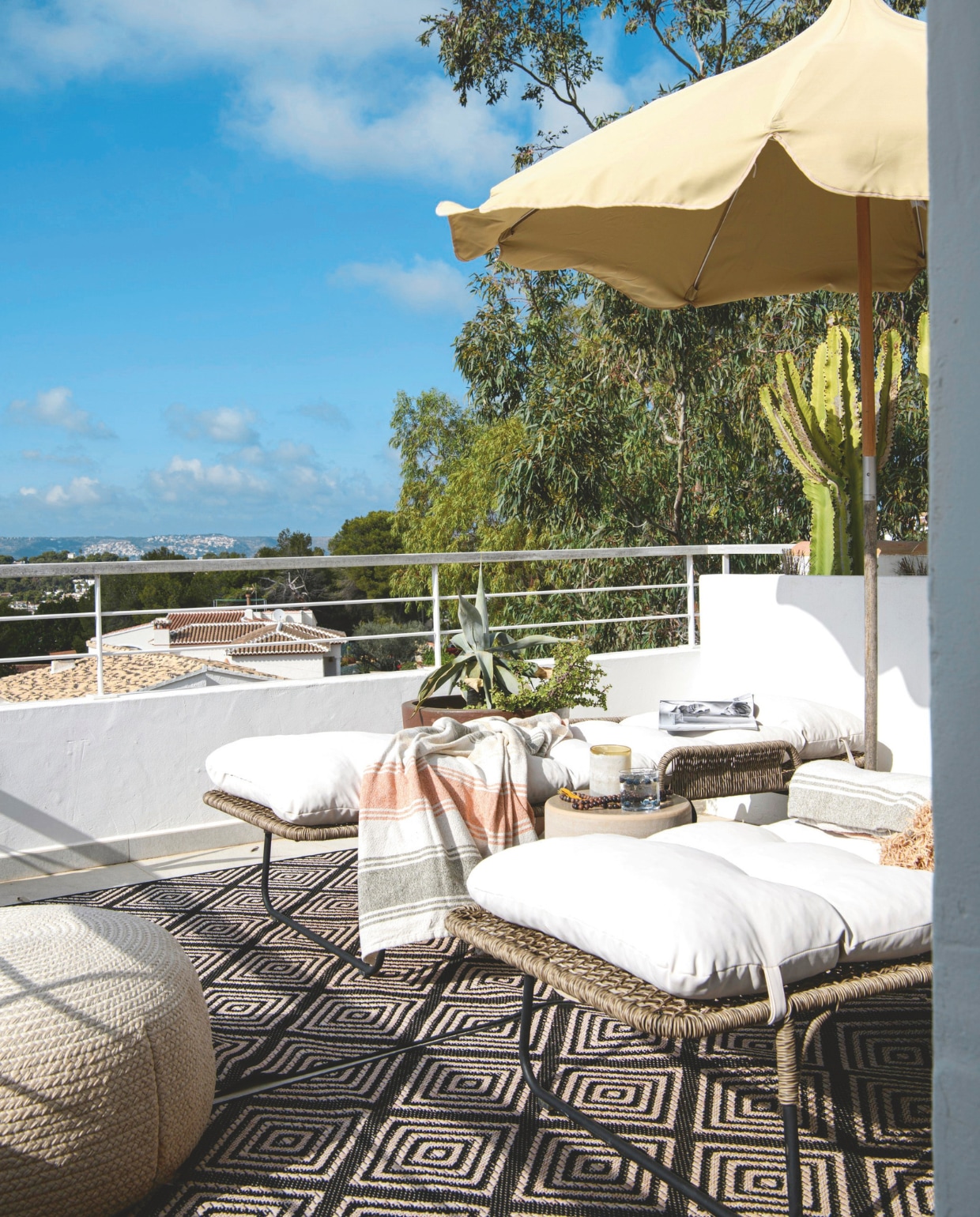 Buitenkleden en plantenbak lokale winkel. Poef Jardinico. Ligbedden Muubs. Ligkussens en handdoeken Haomy. Parasol Ferm Living. Bijzettafel Serax, vtwonen 8-2025 | styling Inge van Lieshout | fotografie Louis Lemaire