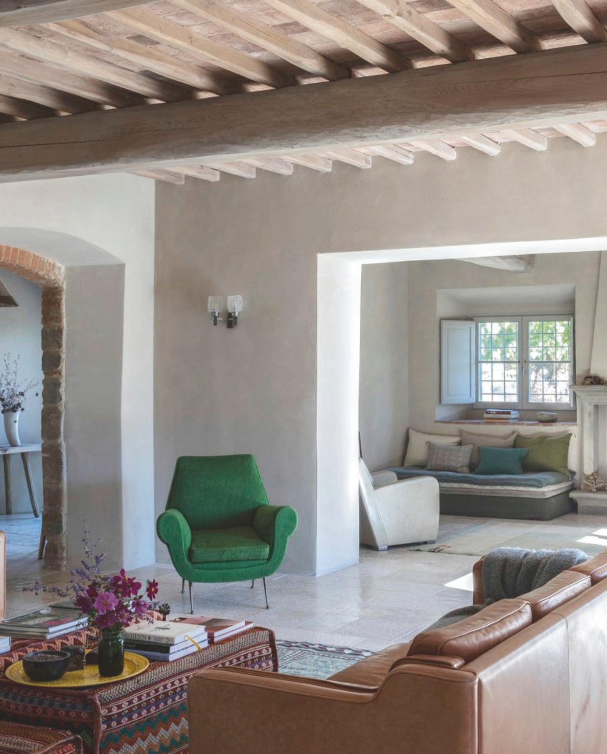 Lauren koos meubels die de architectuur het mooist laten uitkomen. De leren banken komen uit Nederland, de salontafel is samengesteld van poefs, die werden gemaakt van Arabische kameelzadeltassen. De groene fauteuil is vintage Italiaans design van Gigi Radice. De vloer werd gelegd van hergebruikt Trani-steen in ivoorkleur.         vtwonen landelijk 7-2025 | productie Living Inside | fotografie Monica Spezia