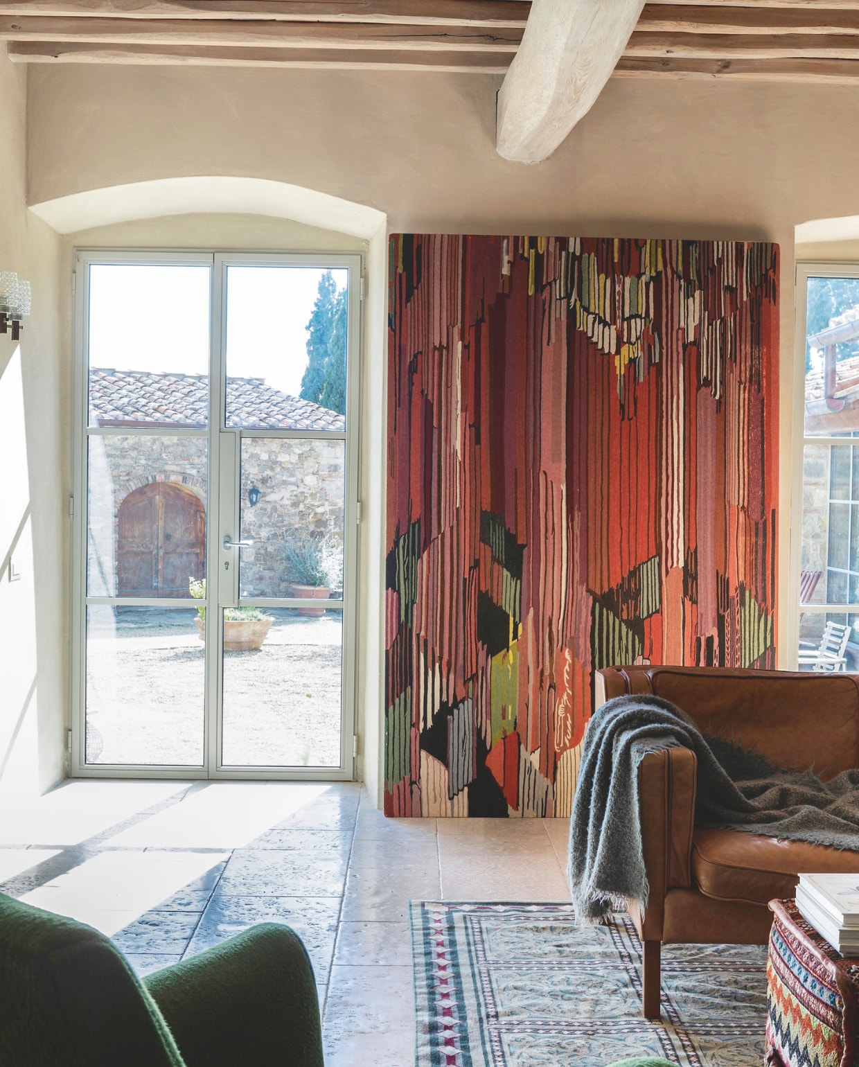 Het wandtapijt is een reproductie van een kunstwerk van František Kupka door Elio Palmisano, via Arredamenti Santiccioli (santiccioli.com). Het is een van de weinige wanddecoraties in het huis. vtwonen landelijk 7-2025 | productie Living Inside | fotografie Monica Spezia