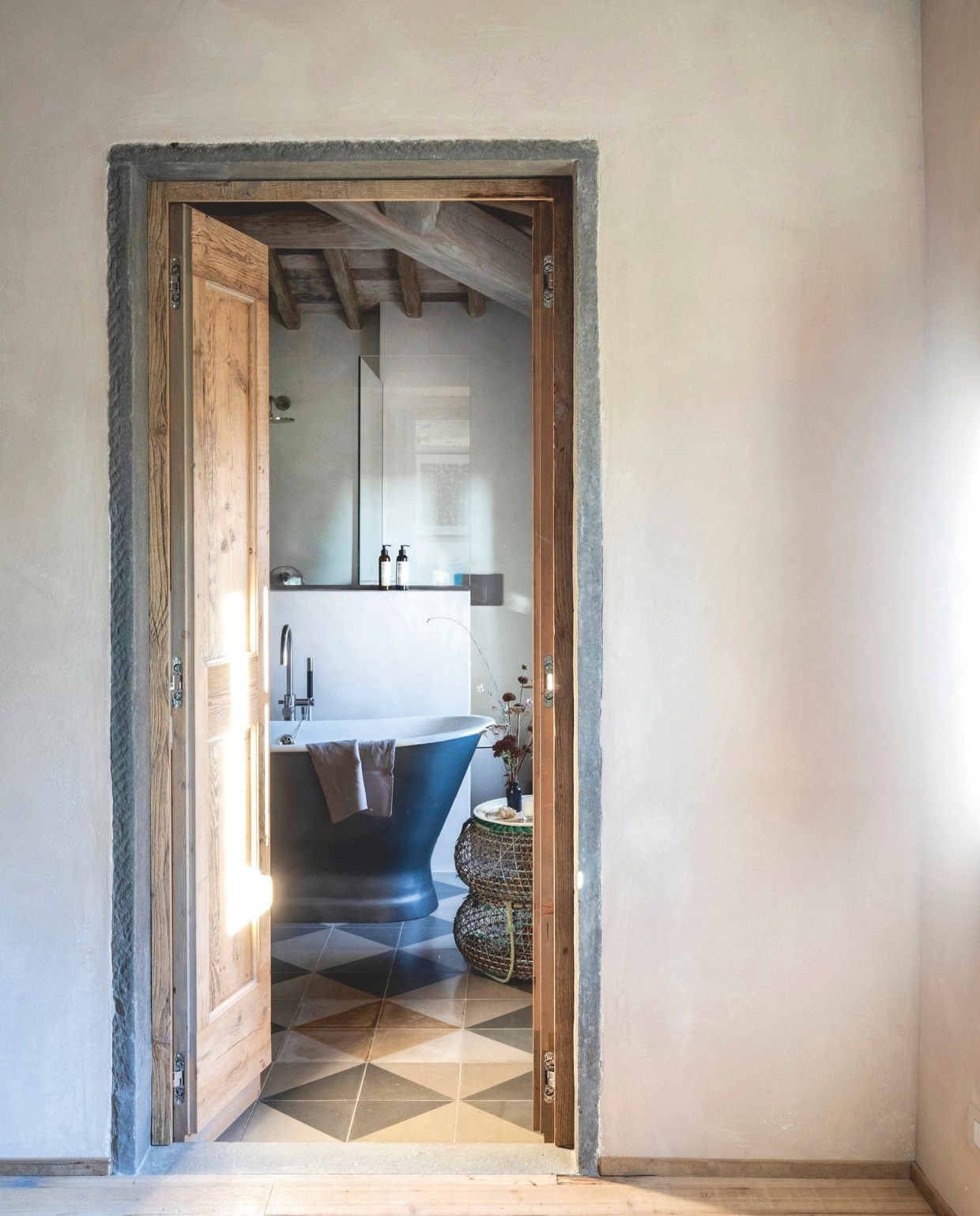 Een vrijstaand geëmailleerd bad siert de badkamer. De deuren en kozijnen zijn van inmiddels prachtig doorleefd hout, het zou eeuwig zonde zijn om ze te verven en daarmee alle sporen van het verleden te wissen.  vtwonen landelijk 7-2025 | productie Living Inside | fotografie Monica Spezia