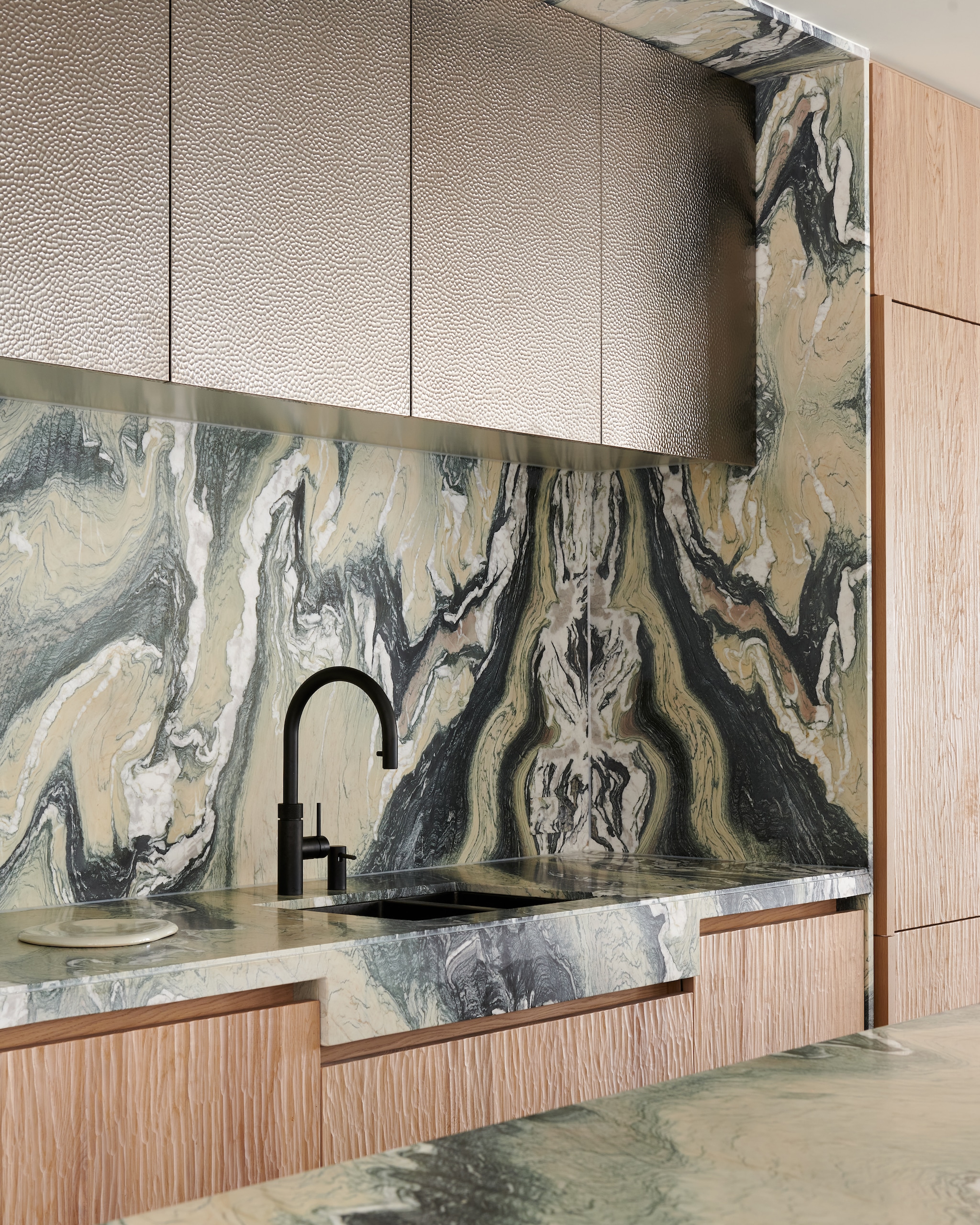 Op maat gemaakte keuken van Framework Studio in kaashout (natuurlijke kleur en gespoten). Details van blauw staal. Hoge kastfronten van geborsteld metaal. Marmeren kookeiland in Cipollino Verde.  Stijlvol Wonen 9-2025 | fotografie Kasia Gatkowska