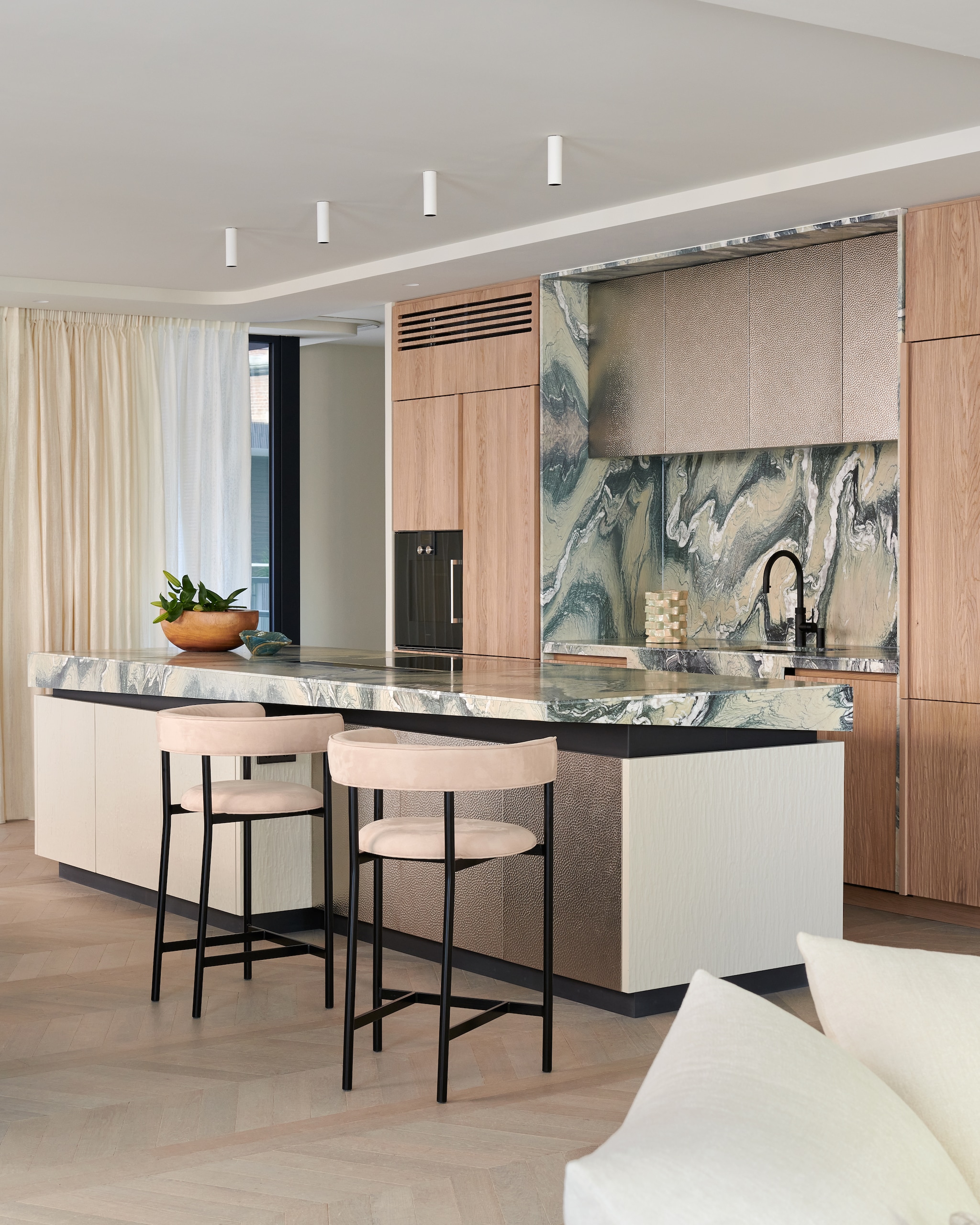 Op maat gemaakte keuken van Framework Studio in kaashout (natuurlijke kleur en gespoten). Details van blauw staal. Hoge kastfronten van geborsteld metaal. Marmeren kookeiland in Cipollino Verde. Verlichting boven kookeiland Kreon. Barkrukken Mobel Copenhagen. Stijlvol Wonen 9-2025 | fotografie Kasia Gatkowska