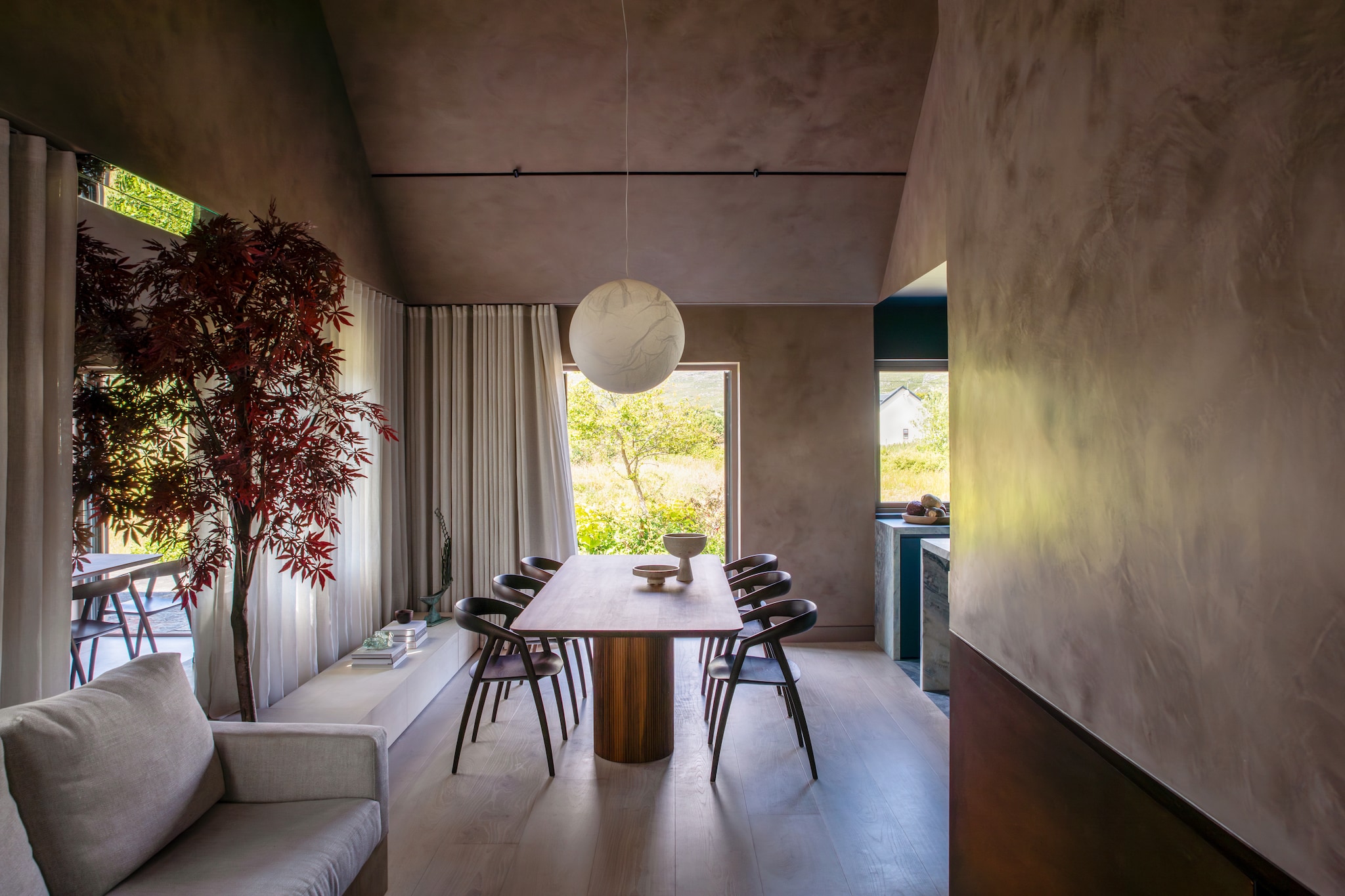 Eettafel Materia. Eetkamerstoelen Inoda + Sveje. Lamp Moon van Davide Groppi. Op maat gemaakte loungebank bekleed met stof van Lizzo. Bijzettafel Parabel van Eero Aarnio. Kleed van  Kelly Wearstler voor The Rug Company.Eikenhouten vloer. Laag eikenhouten dressoir maatwerk. Stijlvol Wonen 10-2025 | fotografie Ruth Maria Murphy