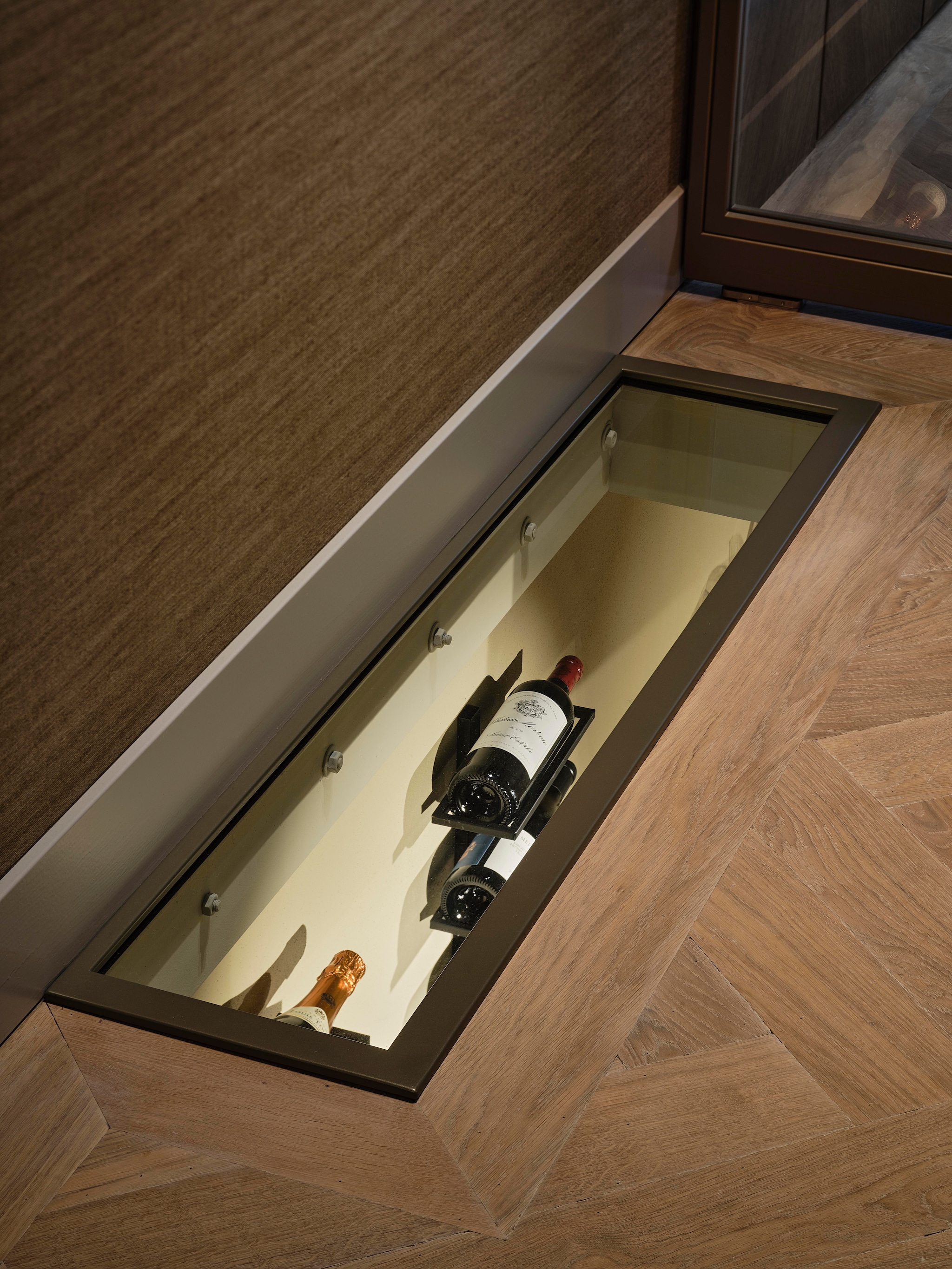 Onder de tuinkamer bevindt zich een wijnkelder. Via een doorkijkje kijk je naar de flessen. Stijlvol wonen 10-2025 | fotografie Space Content Studio