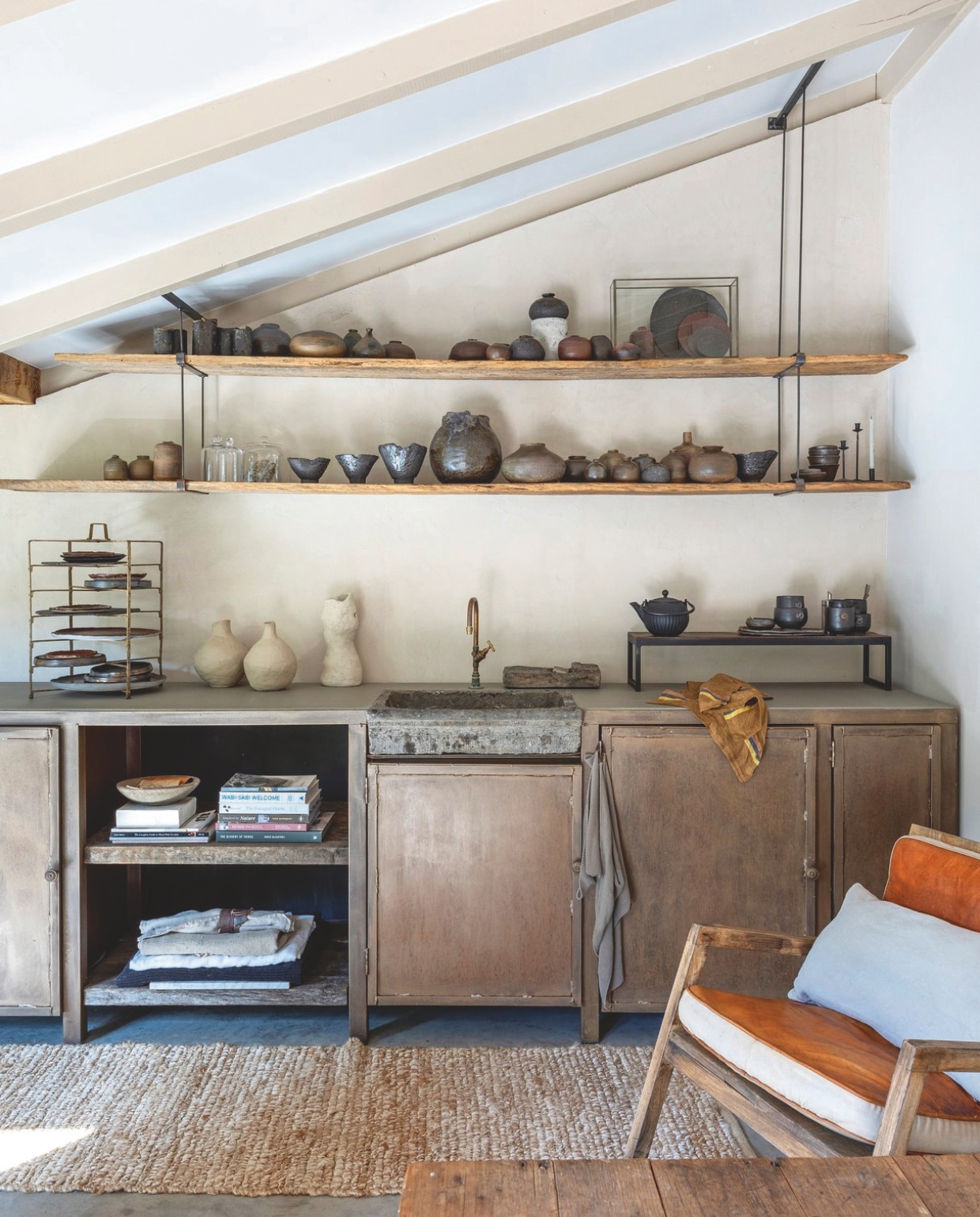 Stalen keuken eigen ontwerp, gemaakt door Adriaan. Kraan Pronck. Zwevende schappen gemaakt door bevriende timmerman. Stoel Marktplaats. Vintage pizzarek curiosamarkt. Vloerkleed Dille en Kamille. Keramiek Atelier Natural Art. vtwonen Landelijk 8-2025 | fotografie Anneke Gambon