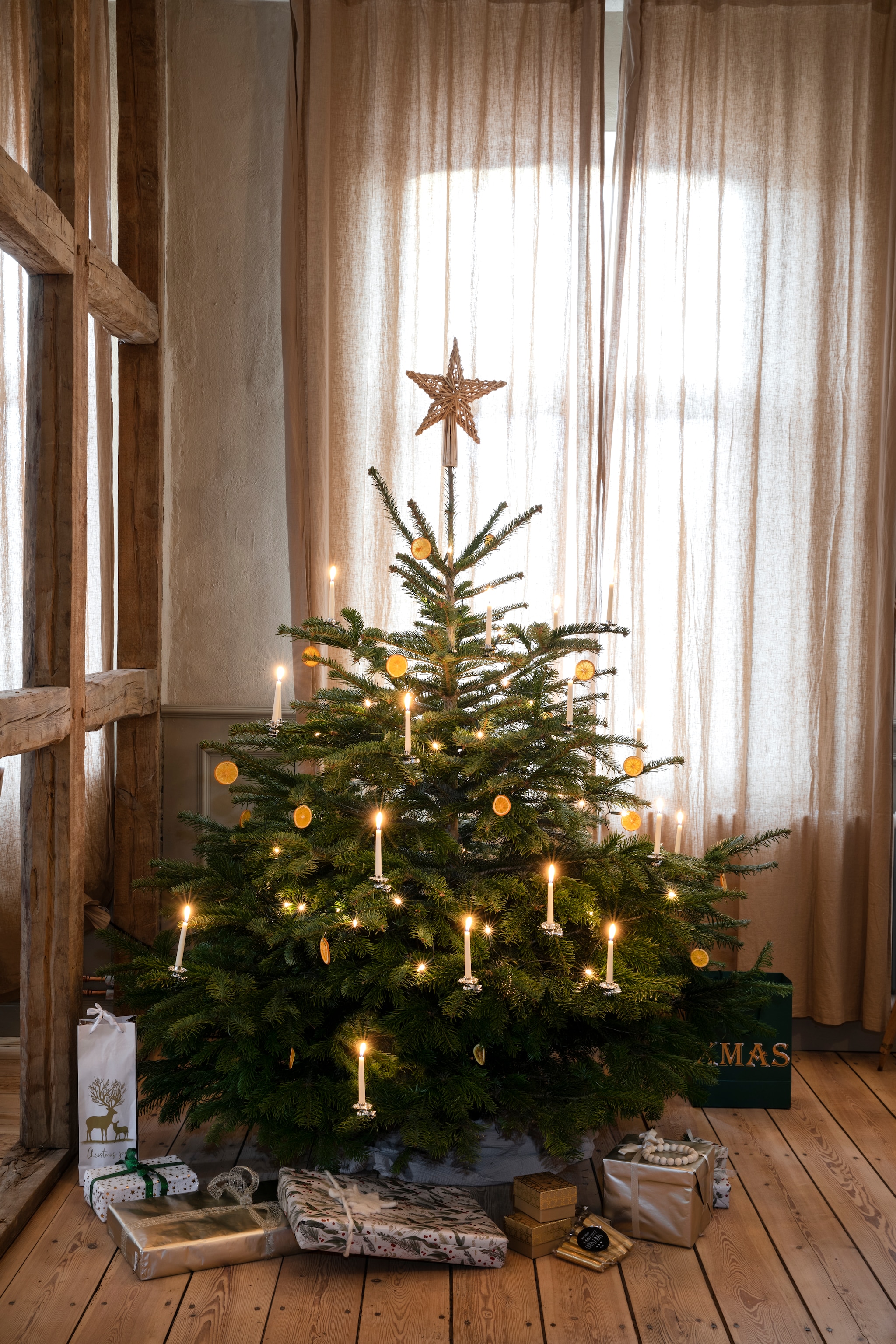 In plaats van ballen hangen er gedroogde sinaasappelschijfjes in de tweede, kleinere kerstboom, ook weer puur natuur en makkelijk zelf te maken. vtwonen Landelijk 11-2025 | styling Miriam Hannemann | fotografie André Reuter