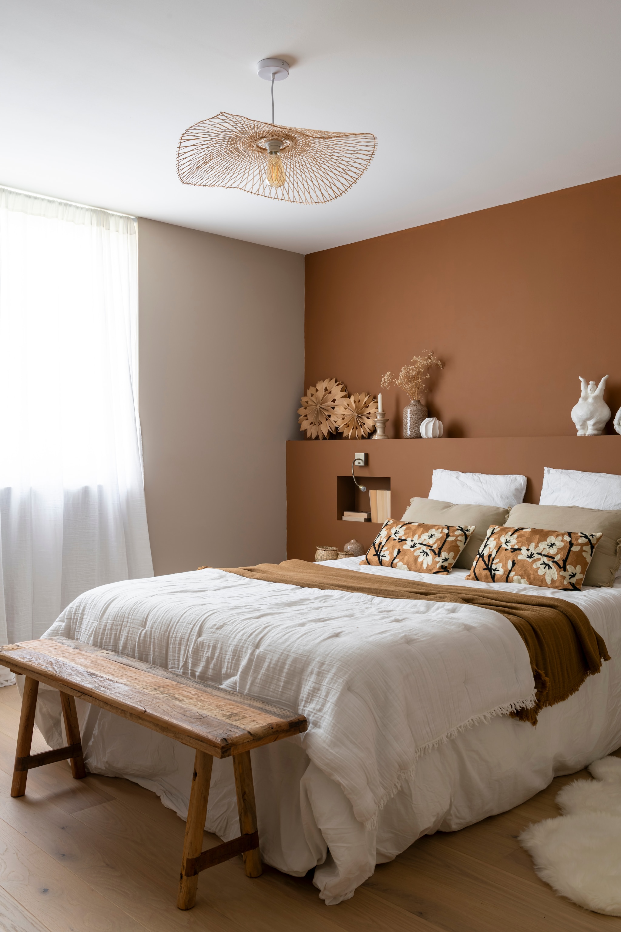 Terracotta muurkleur Affogato van Little Greene. Kruk, hanglamp, bank, vloerkleed, gordijnen, vazen, kandelaars en decoratieve objecten Beau Lieu. Beddengoed Haomy. vtwonen Landelijk 11-2025 | styling Amandine Berthon | fotografie Julien Fernandez