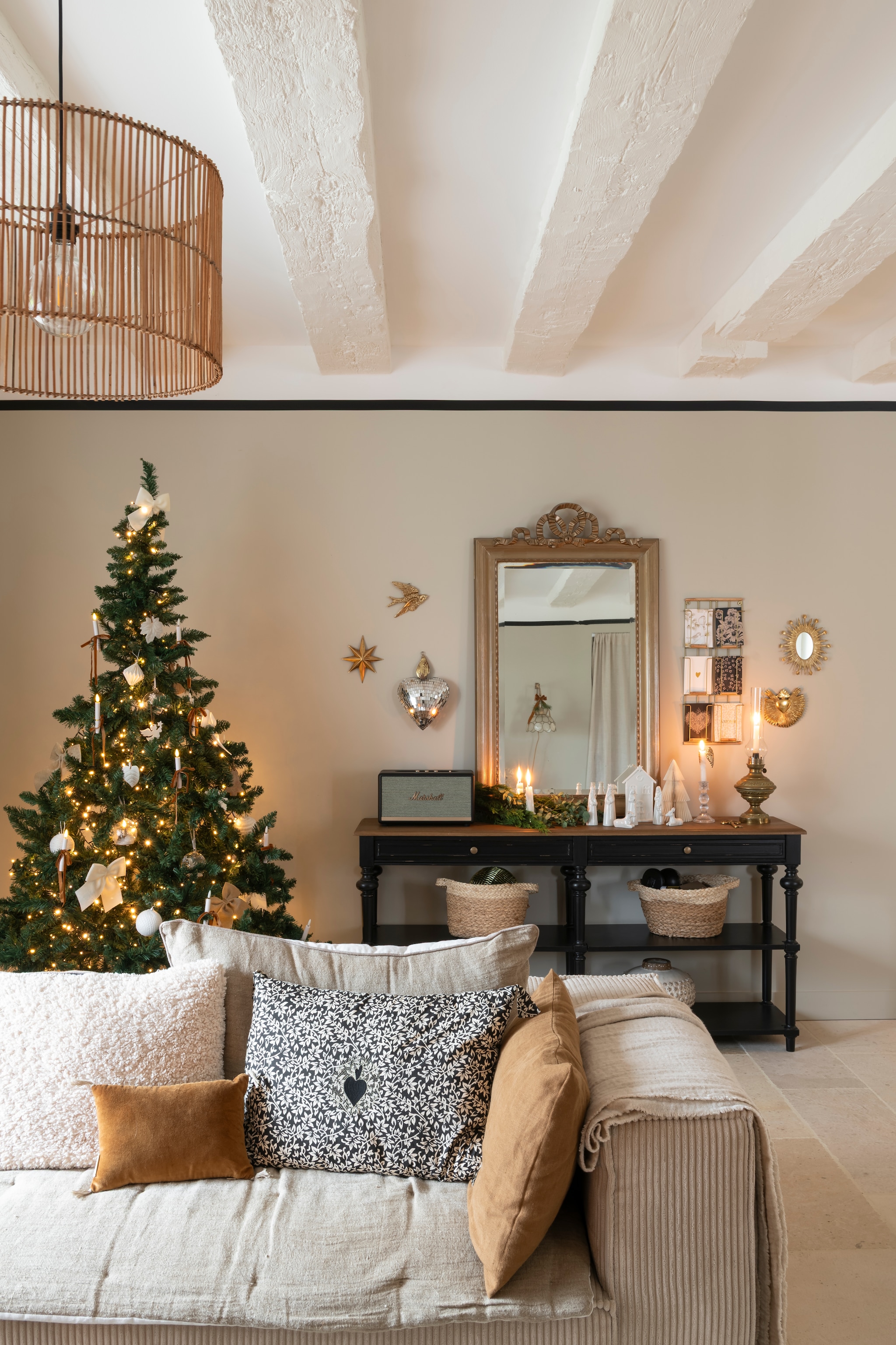 Spiegel familiebezit. Consoletafel, bankhoes, wanddecoraties, hanglamp en porseleinen kerststal Beau Lieu. Bank La Redoute. Kussens Boncoeurs. Vloerkleed Vivaraise. Muurverf Portland Stone van Little Greene. vtwonen Landelijk 11-2025 | styling Amandine Berthon | fotografie Julien Fernandez