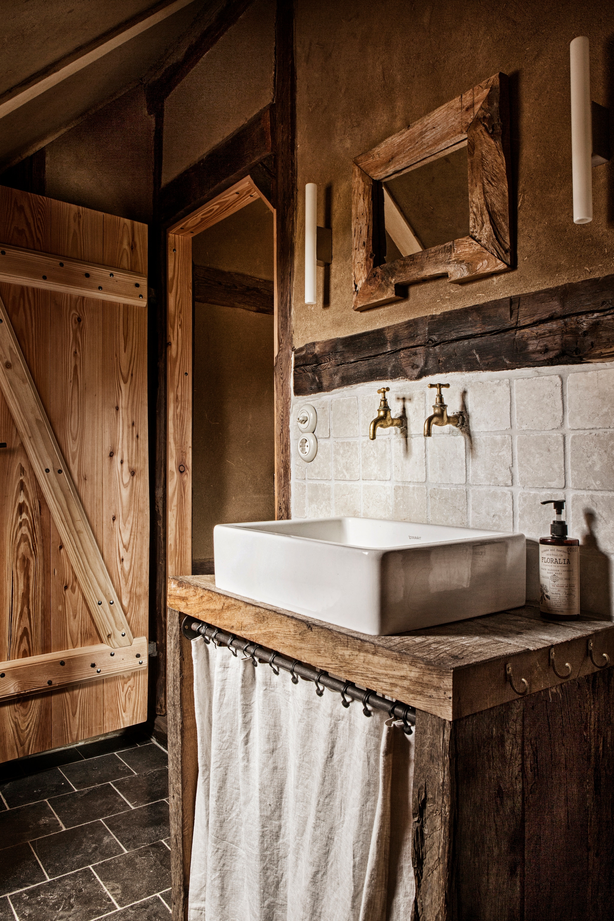 Voor de badkamer heeft een timmerman een wastafel gemaakt van hergebruikt hout. De tegels zijn gemaakt naar een historisch model, soortgelijke bij Sanitairkamer. Kranen antiek. vtwonen landelijk 11-2025 | productie The Country House | styling Miriam Hannemann | fotografie André Reuter