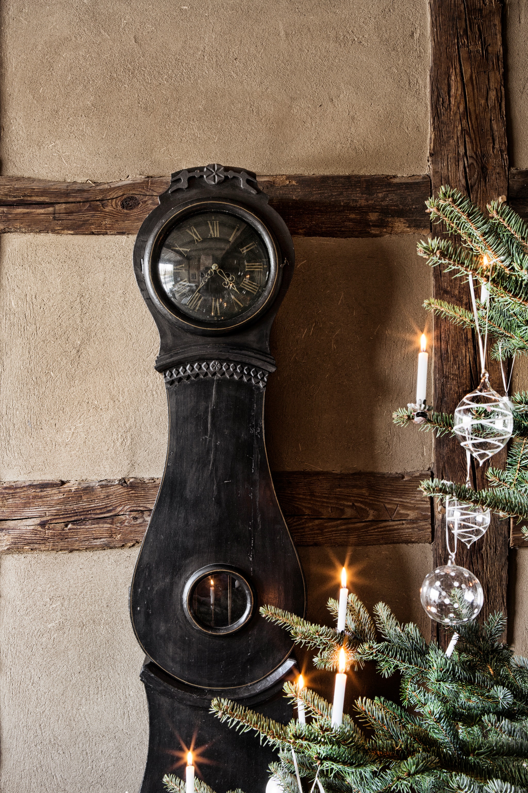 Zweedse Mora klok van klokkenmaker. Kerstballen Grüne Erde. Muur leemstucwerk. Soortgelijke kerstboomkaarsjes Het Bijenhuis. vtwonen landelijk 11-2025 | productie The Country House | styling Miriam Hannemann | fotografie André Reuter
