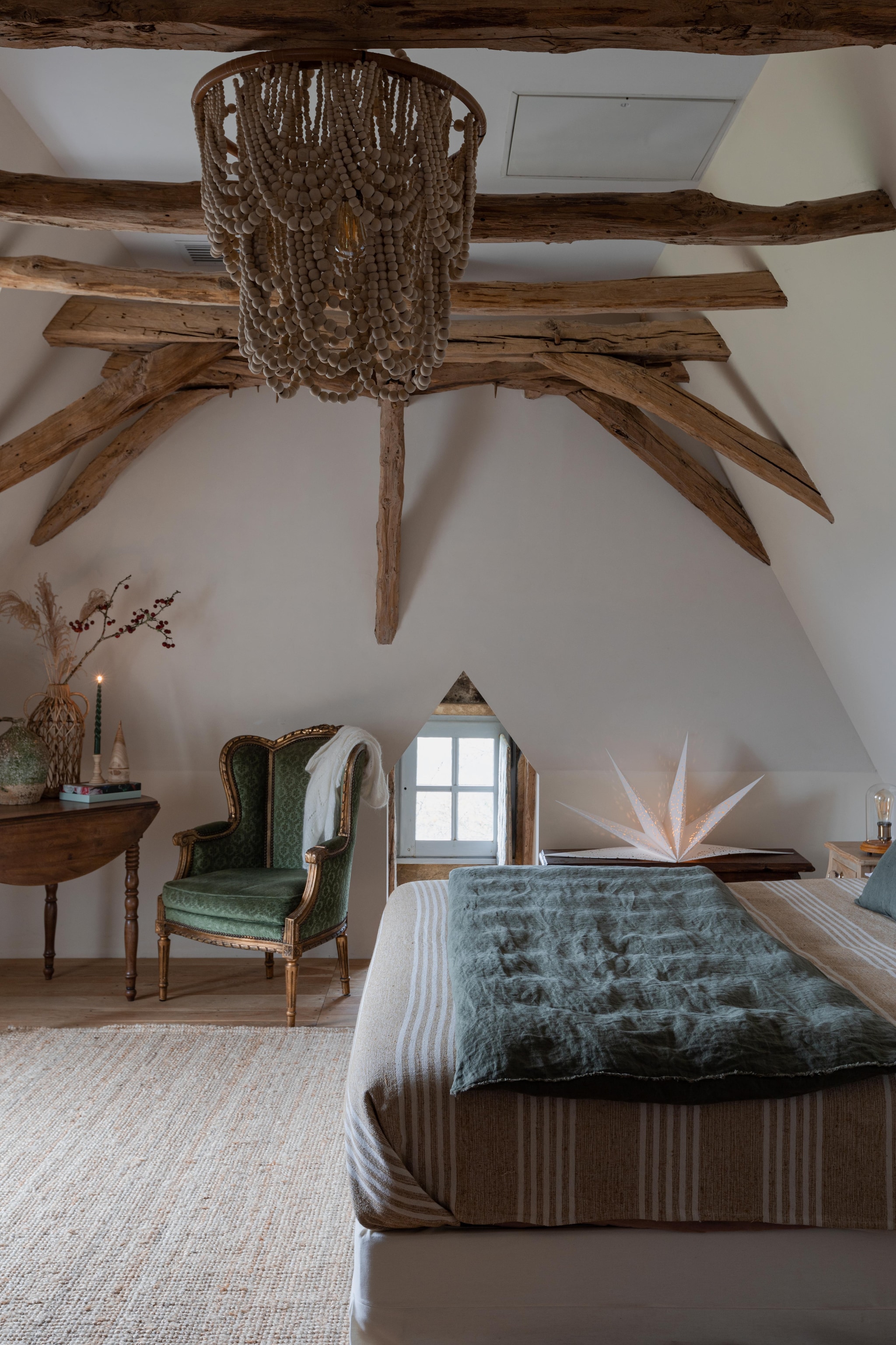 De antieke tafel was een eettafel. Rieten vaas Madam Stoltz. De kruik werd gebruikt voor walnootolie, een streek-product. Plafondlamp met de hand gemaakt in Indonesië. Kerstster Nordic Nest. Stoel met originele bekleding uit een plaatselijke antiekwinkel. vtwonen Landelijk 11-2025 | styling Wilma Custers | fotografie Fabienne Delafraye