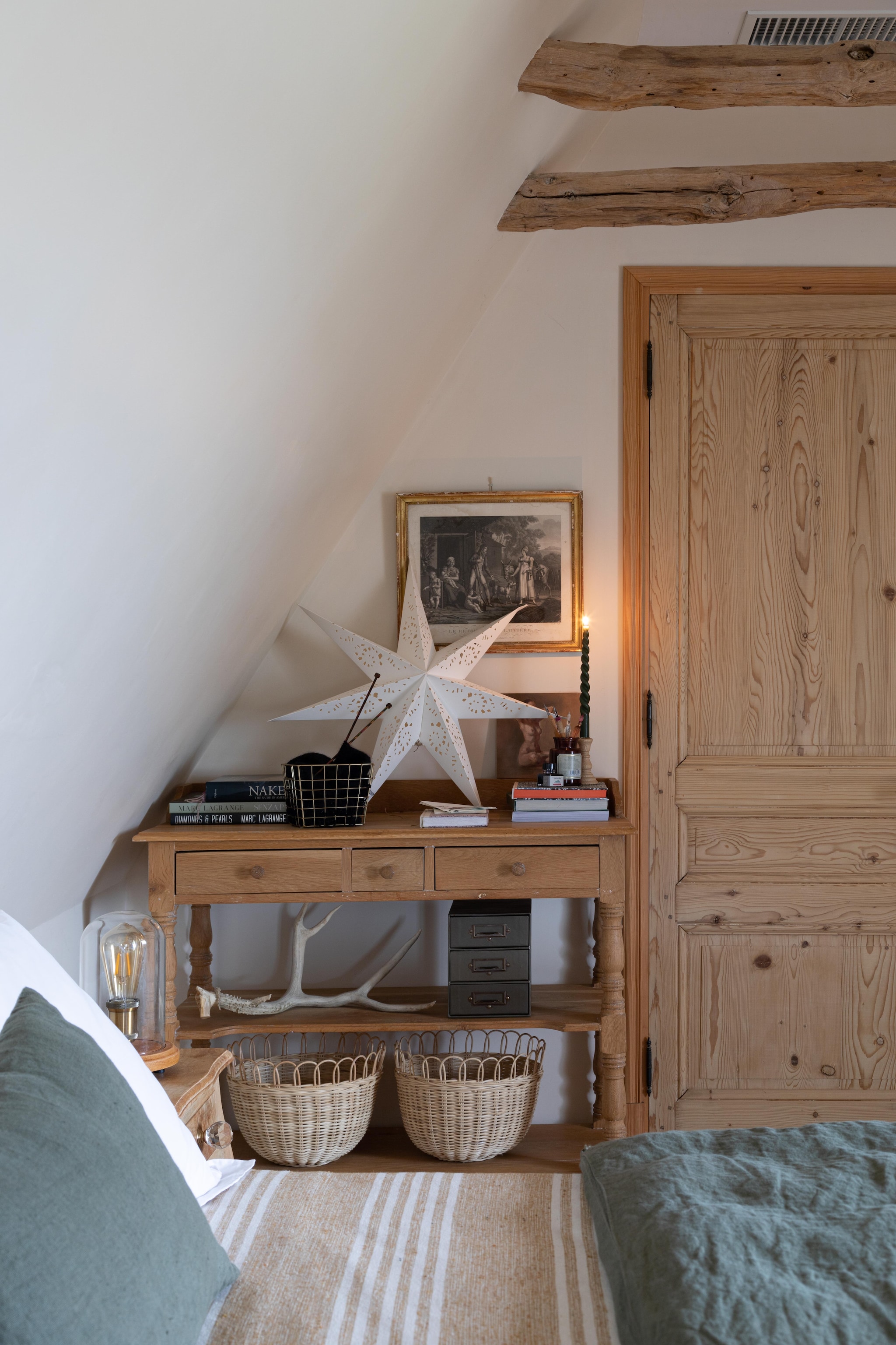 Een van de gastenkamers opzolder. De dwarsbalken geven de ruimte extra karakter. Boerentafel als kaptafel. Bed Ikea. Kerstster Nordic Nest. Beddengoed Harmony en Muy Mucho. vtwonen Landelijk 11-2025 | styling Wilma Custers | fotografie Fabienne Delafraye