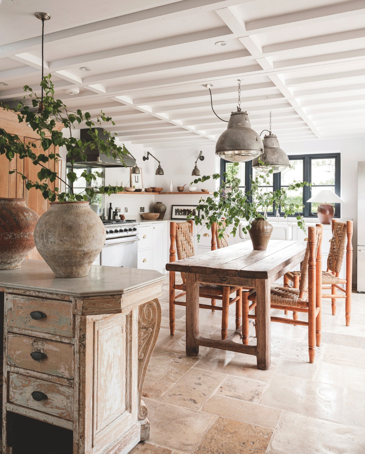 Plafond en muur verfkleur Yes Your Honour van Fired Earth. Kasten, wandlampen, tafellamp, kandelaars Anton & K. Vloer hergebruikte Cotswolds-steen. Keuken op maat gemaakt. Touwstoelen Audoux & Minet. Franse patisserietafel, lampen, Chinese voorraadpot, vazen, Zweedse folkart kom antiek. Hanglampen NorfolkDecorative Antiques. Fornuis Falcon. Tafel uit Frankrijk. vtwonen landelijk 8-2025 | productie Living Inside | styling Ali Heath | fotografie Emma Lewis