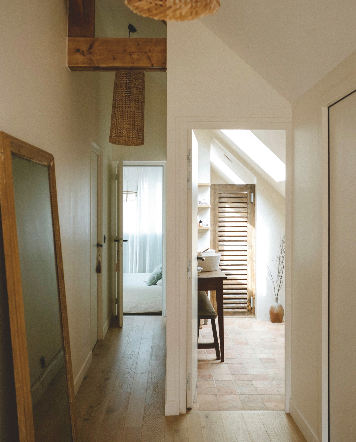 Doorkijk op de overloop naar de badkamer en slaapkamer. Spiegel Désuet, soortgelijke spiegels Hübsch Interior. Rieten hanglamp Baan Baan. vtwonen landelijk | styling Florence Poncet | fotografie Julien Hay