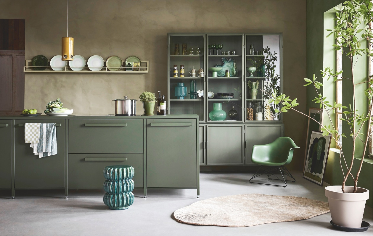 Lab Paint kalkverf, links Limited Jade en rechts Tokyo Tea, 1 liter € 66,-(vestingh.nl). Keuk keuken, groen bovenblad, met basisapparatuur vanaf € 5000,- (keuk.nl). New Routz buffetkast Garland, metaal, olijfgroen, 183x43x222 cm (bxdxh) € 2495,-, Pstr Store poster Woodblock Print III, papier, wit en groen, 70x100 cm € 83,-, poster Grove van Marco Marella, papier, wit en groen, 50x50 cm € 58,- (shop.vtwonen.nl). Vitra loungestoel Lar, kunststof en metaal, 62,5x61x63,5cm (bxdxh) € 565,- (loods5.nl). Casalis vloerkleed, textiel, naturel, prijs op aanvraag (casalis.be). Polspotten bijzettafel Pumpkin, aardewerk, groen € 220,- (polspotten.nl). Servies in de kast en op het schap: HKliving hoge glazen 70’s L, groen, set van 4 € 39,-, glazen 70’s bulb, lichtgroen, set van 4 € 30,-, wijnglazen, groen, set van 4 € 46,95, laag glas Tube, olijfgroen € 8,50, karaf Tube, olijfgroen € 19,95, bekers, aardewerk, geel en bruin € 19,95, koffiekop met oor, aardewerk, bruin € 8,75, beker, aardewerk, groen en bruin € 7,50, schaal op voet The Emerald, aardewerk, groen € 54,99, schaaltje Oyster, aardewerk, groen € 25,-, schaal Shell, aardewerk, blauw en groen € 72,-, schaal op voet, aardewerk, privébezit, bord 70’s, aardewerk, zachtgroen € 27,95, bord Chef, groen € 15,-, bord The Emeralds, donkergroen € 24,95, hanglamp Ceramic, aardewerk, oker € 149,- (hkliving.nl). Urban Nature Culture vaas, gerecycled glas, transparant € 14,99, vaas,gerecycled glas, flessengroen € 29,99, vaas Collo Reseda M, glas, lichtgroen € 39,95, kandelaar Sopra, bol glas, olijfgroen € 24,99 (shop.vtwonen.nl). Ansichtkaarten € 1,- (artunlimited.nl). Ikea pan Hemkomst, aluminium € 49,95, voorraadpot Korken in de kast € 2,79 (ikea.com). Theedoeken, katoen, groen en wit € 7,95 (dille-kamille.nl). Planten met pot en oude schaal op voet privébezit. vtwonen 09-2025 | styling Marianne luning | fotografie Alexander van Berge