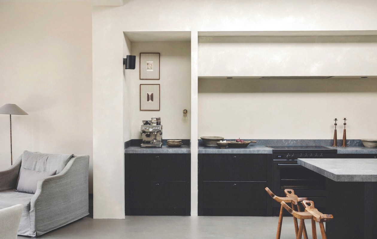 Keramieken Saskia Knaapen. Stenen schalen antiek. Museumkunstkaarten Antoni Tàpies uit Barcelona, ingelijst in lijst met linnen passe-partout van Passe-partout Shop. Maatwerk keuken met houten frontjes en natuurstenen blad Akzent Küchen. Inductiefornuis Boretti MLI95XMAT. Spot Serax. Maatwerk inbouwkasten en planken Meubels Van Zant. Vintage houten krukken Marktplaats. vtwonen landelijk 8-2025 | fotografie Stie De Neve