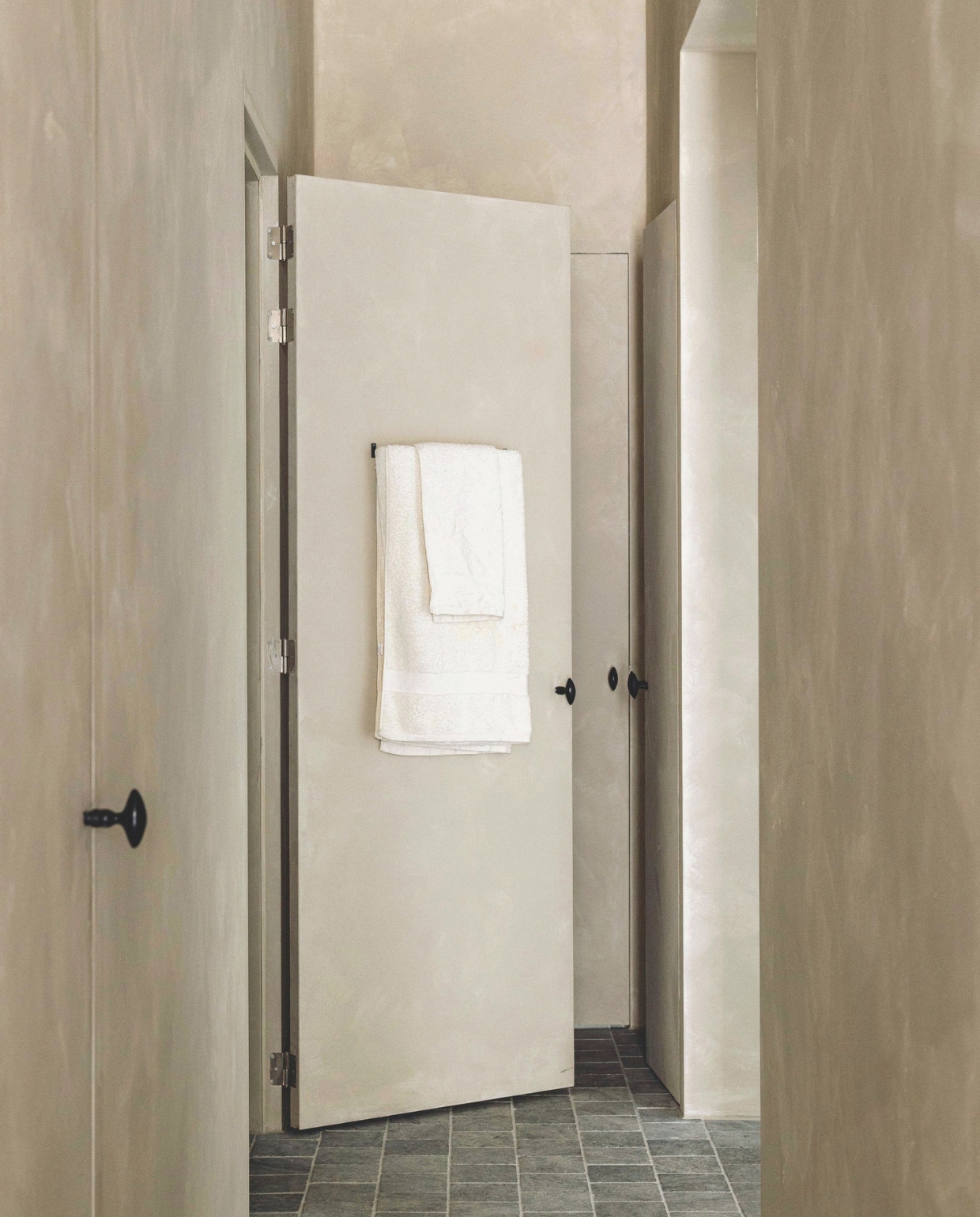 Deuren en muren betonverf in Silk van Beton Cire Webshop. Belgisch hardstenen tegels antiek. Handdoekrek Zara Home. Spot Serax. vtwonen landelijk 8-2025 | fotografie Stie De Neve