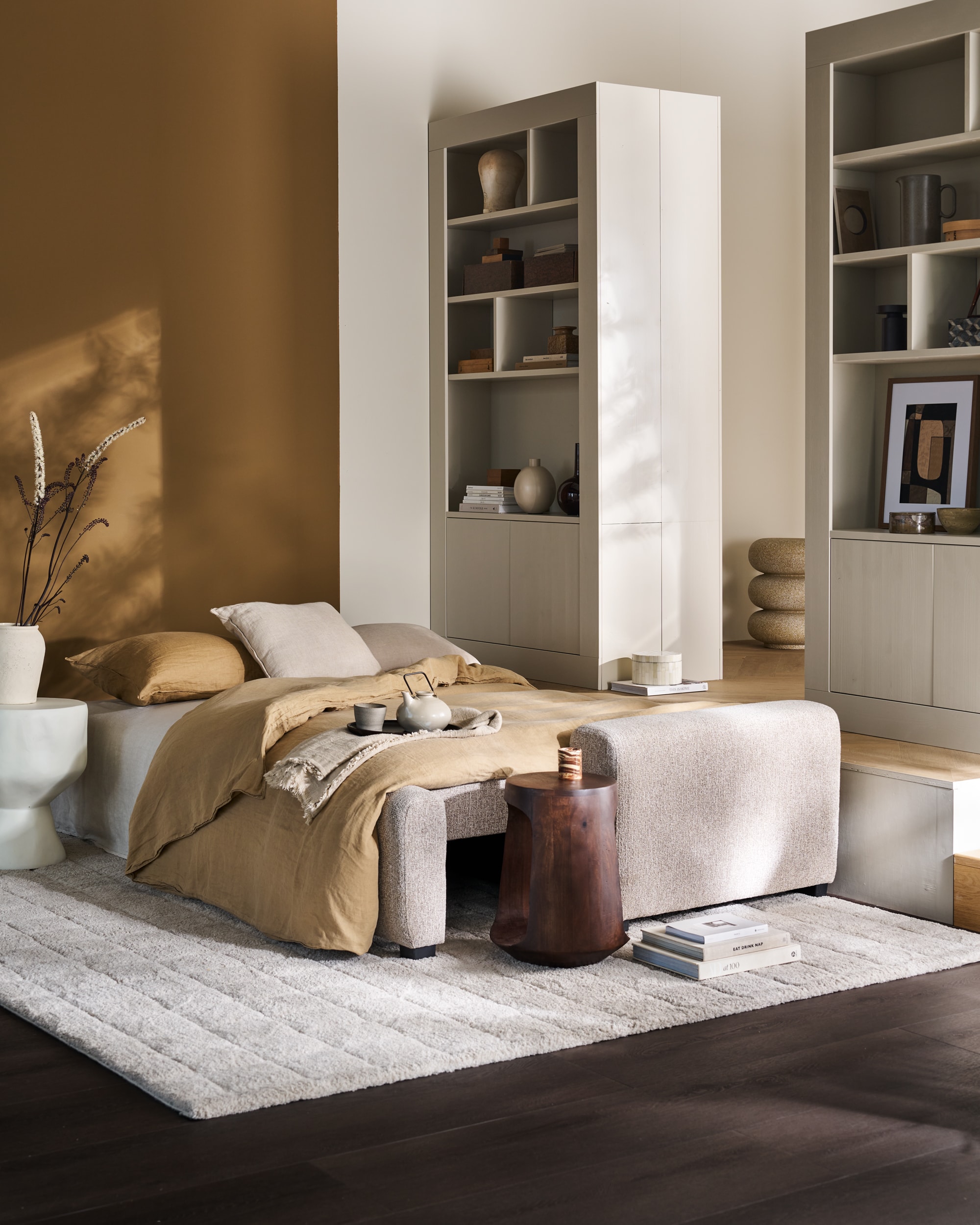 vtwonen wandkast Wallcover, grenen, dust, 117x31x229 cm (bxdxh), per stuk € 799,-, vtwonen 3-zitsslaapbank Night&Day, Pes, naturel melange, 239x107x85 cm (bxdxh), uitgeklapt 239x145x85 cm (bxdxh)€ 1349,-, vtwonen poef Pearl XL, melange stof, naturel, 80x28 cm (Øxh)€ 199,-.M.m.v. woood.nl (bijzettafels, kussen met dessin), weldaad.com (linnen kussen), vansand.nl (Little Greene muurverf Light Bronze Green no. 123), urbannatureculture.com (witte vaas), burbriantiek.nl (archiefdozen), ilsevanstoltz.com (art prints), yumeko (dekbedovertrekset).  Vloerkleed Blocks van vtwonen (shop.vtwonen.nl). Overig privébezit. vtwonen 11-2025 | styling Cleo Scheulderman | fotografie Jeroen Van der Spek