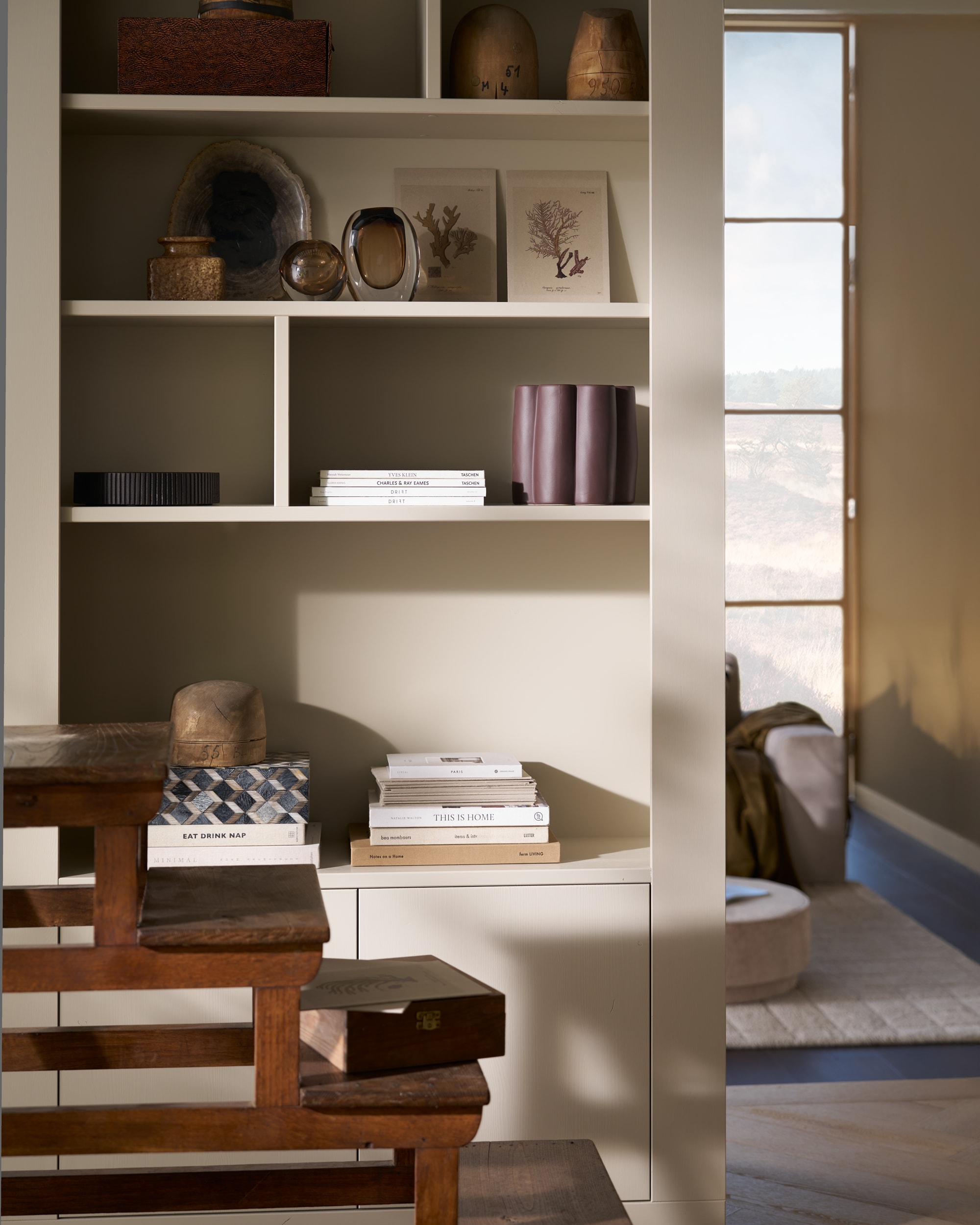 vtwonen wandkast Wallcover, grenen, dust, 117x31x229 cm (bxdxh), per stuk € 799,-, vtwonen poef Pearl en poef Pearl XL, melange stof, naturel, 40x45 cm (Øxh) € 199,- en 80x28 cm (Øxh)€ 199,-, vtwonen salontafel Coffee A Gogo, mangohout, walnoot, 90x40 cm (Øxh) € 499,- en vtwonen 2,5-zitselementenbank Family, geweven stof, zand, 298x98x85 cm (bxdxh) € 1999,-.M.m.v. pietjonker.nl (bibliotheektrap, bijzettafel), hm.com (grafisch kussen), weldaad.com (servies, opbergmand, linnen kussens), burbriantiek.nl (kruiken), vtwonen.nl (visgraat laminaat Rafter, vloerkleed Blocks). Overig privébezit.