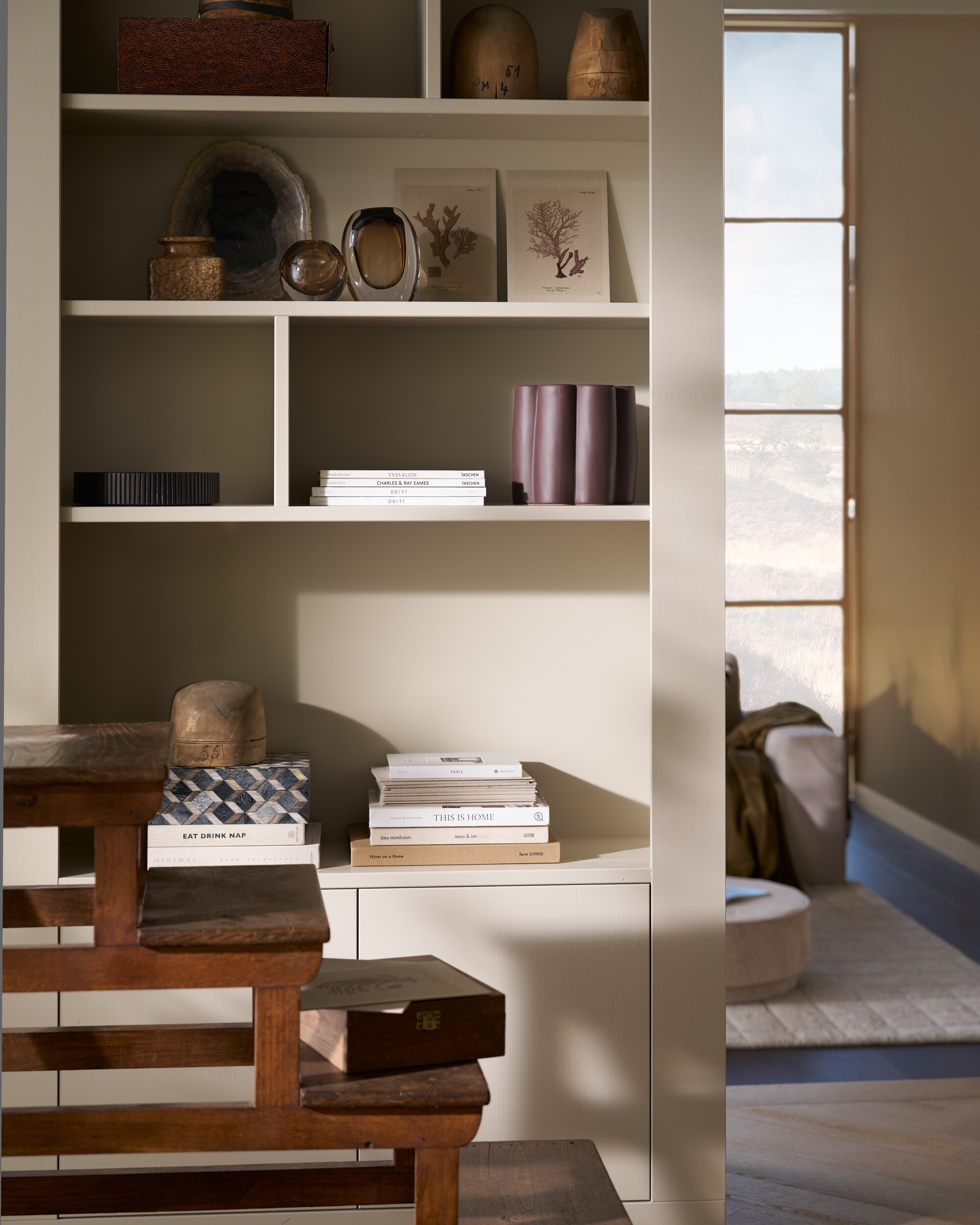 vtwonen wandkast Wallcover, grenen, dust, 117x31x229 cm (bxdxh), per stuk € 799,-, vtwonen poef Pearl en poef Pearl XL, melange stof, naturel, 40x45 cm (Øxh) € 199,- en 80x28 cm (Øxh)€ 199,-, vtwonen salontafel Coffee A Gogo, mangohout, walnoot, 90x40 cm (Øxh) € 499,- en vtwonen 2,5-zitselementenbank Family, geweven stof, zand, 298x98x85 cm (bxdxh) € 1999,-.M.m.v. pietjonker.nl (bibliotheektrap, bijzettafel), hm.com (grafisch kussen), weldaad.com (servies, opbergmand, linnen kussens), burbriantiek.nl (kruiken), vtwonen.nl (visgraat laminaat Rafter, vloerkleed Blocks). Overig privébezit. vtwonen 11-2025 | styling Cleo Scheulderman | fotografie Jeroen Van der Spek