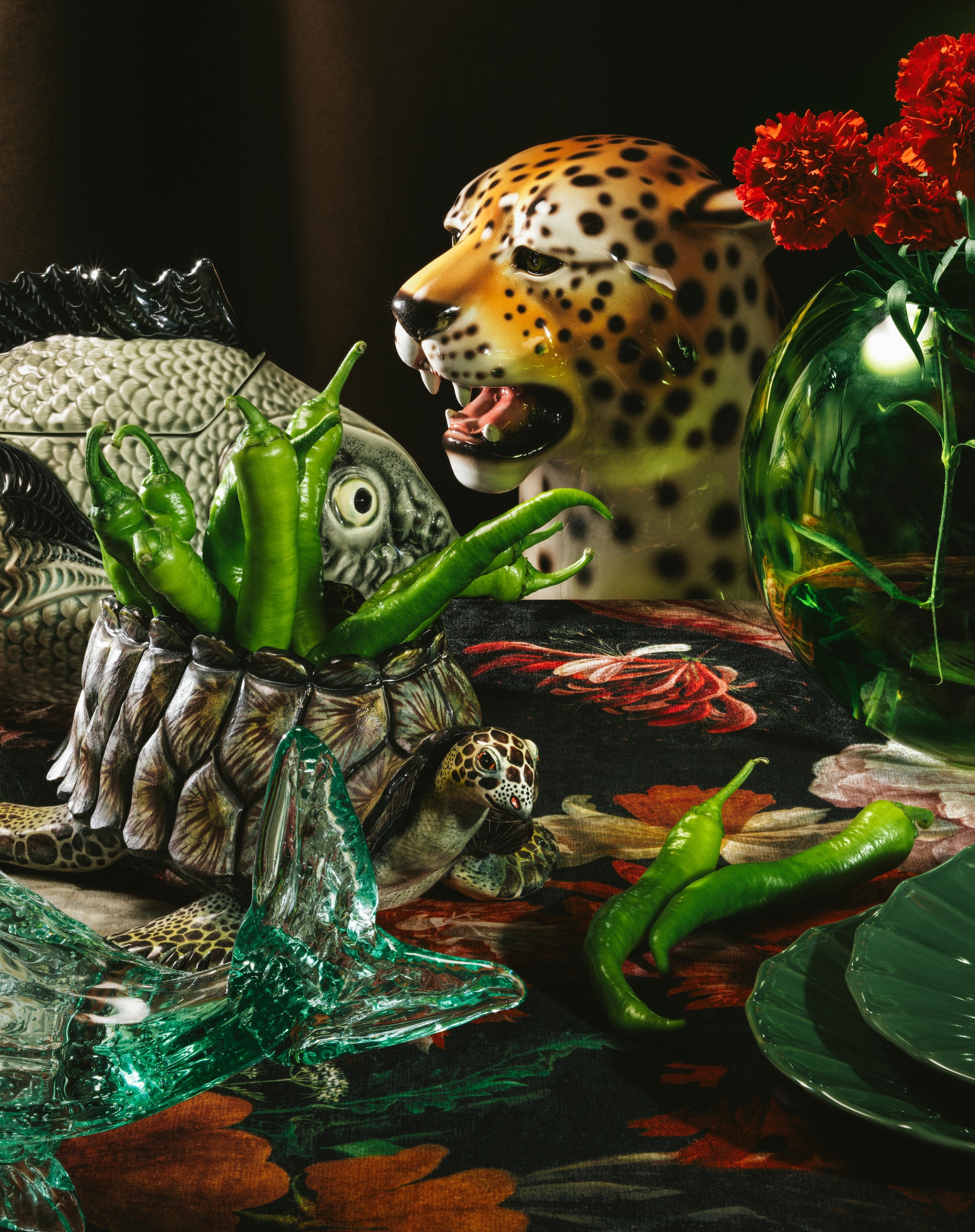 Supermatique panter, handbeschilderde keramiek, 70 cm (h) € 335,- (supermatique.com). Bordallo Pinheiro serveerschaal met deksel vis, aardewerk € 169,- (arket.com). Polspotten pot met deksel Bloated, glas, set van 4 € 350,-, pot vis, glas € 100,- (polspotten.nl). Ardmore serveerschaal met deksel Schildpad, handbeschilderde keramiek € 1250,- (thewunderkammerwebshop.com). Ikea borden Mävinn, met plissé rand € 15,- (ikea.com). Kniphal tafelkleed (kniphal.nl). Stijlvol Wonen 10-2025 | Styling Djamilla van Brussel | Fotografie Benning & Gladkova