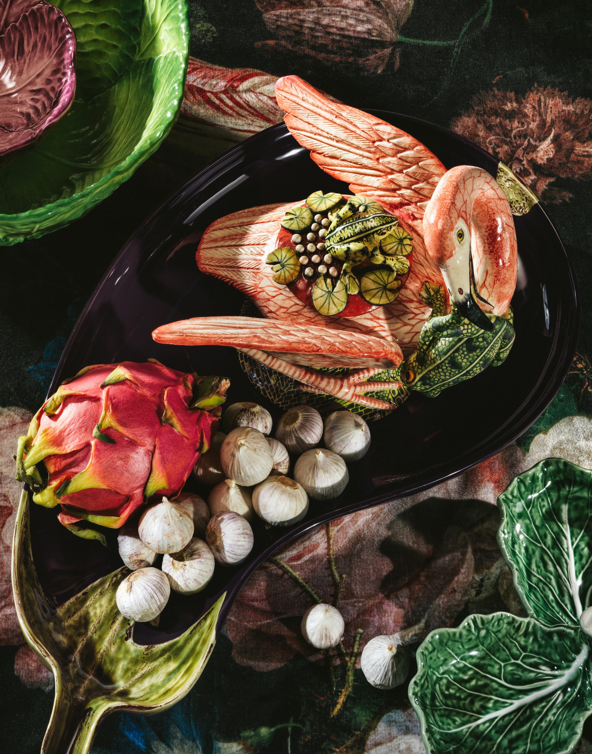 Au Bain Marie saladeschaal groene kool, aardewerk, groen € 90,-, schaaltje rode kool, aardewerk € 32,-, Bordallo Pinheiro serveerschaalaubergine, aardewerk € 45,- (supermatique.com). Ardmore serveerschaal met deksel flamingo enkikker, beschilderd keramiek € 985,-(thewunderkammerwebshop.com). Bordallo Pinheiro serveerschaal kool, groen € 28,- (debijenkorf.nl). Kniphal tafelkleed (kniphal.nl). Stijlvol Wonen 10-2025 | Styling Djamilla van Brussel | Fotografie Benning & Gladkova