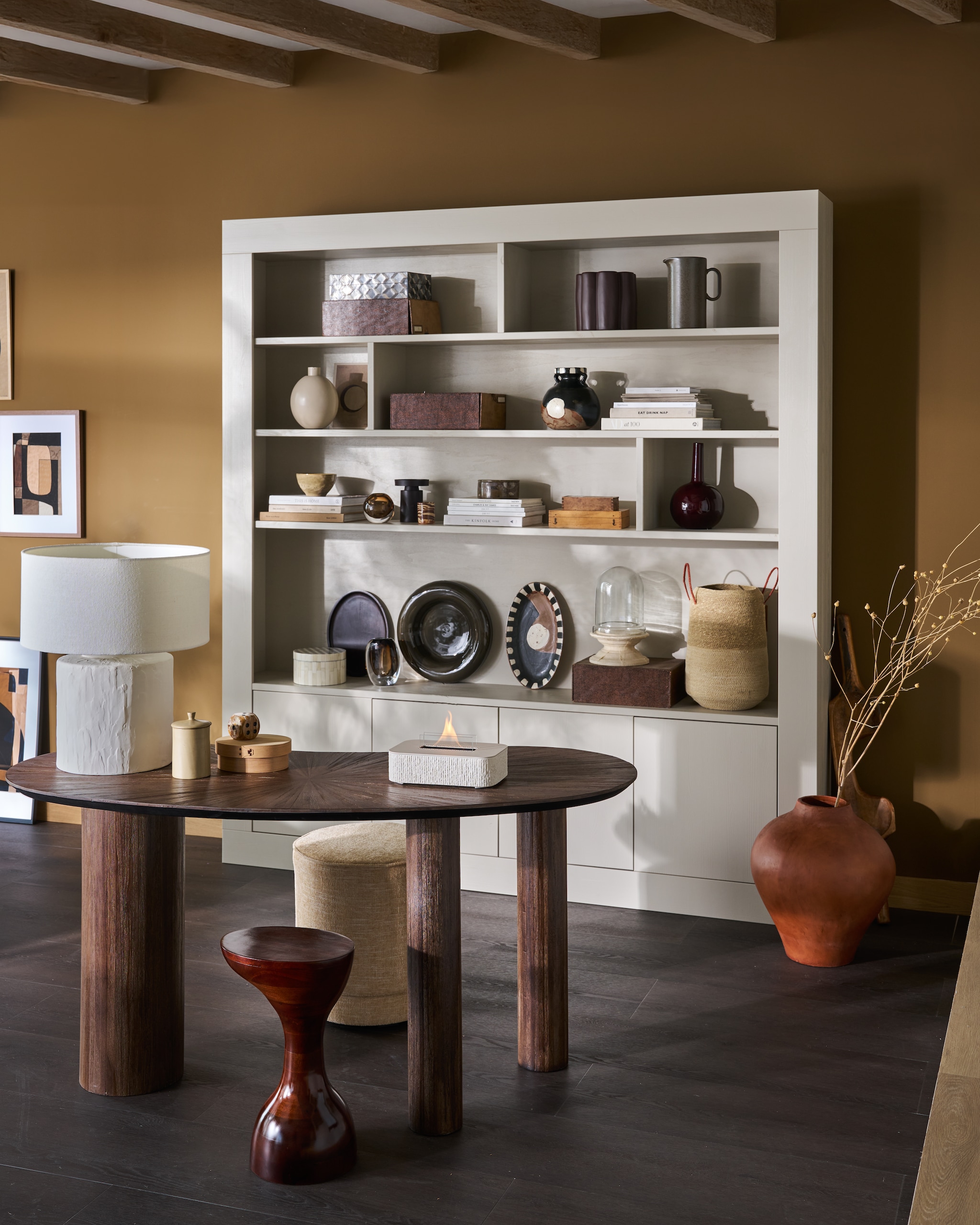 vtwonen wandkast Wallcover, grenen, dust, 210x31x229 cm (bxdxh) € 1499,-, vtwonen poef Pearl, melange stof, naturel, 40x45 cm (Øxh) € 199,-.M.m.v. woood.nl (bureau), urbannatureculture.com (tafellamp, bijzettafel, oranje pot, geschulpte paarse bloempot, donkergroene schaal), vansand.nl (Little Greene muurverf Light Bronze Green no. 123), zarahome.com (ovalen schalen, beschilderde vaas), burbriantiek.nl (archiefdozen), weldaad.com (stolp op voet, mand). Aubergine kandelaar van vtwonen (shop.vtwonen.nl). Overig privébezit. vtwonen 11-2025 | styling Cleo Scheulderman | fotografie Jeroen Van der Spek