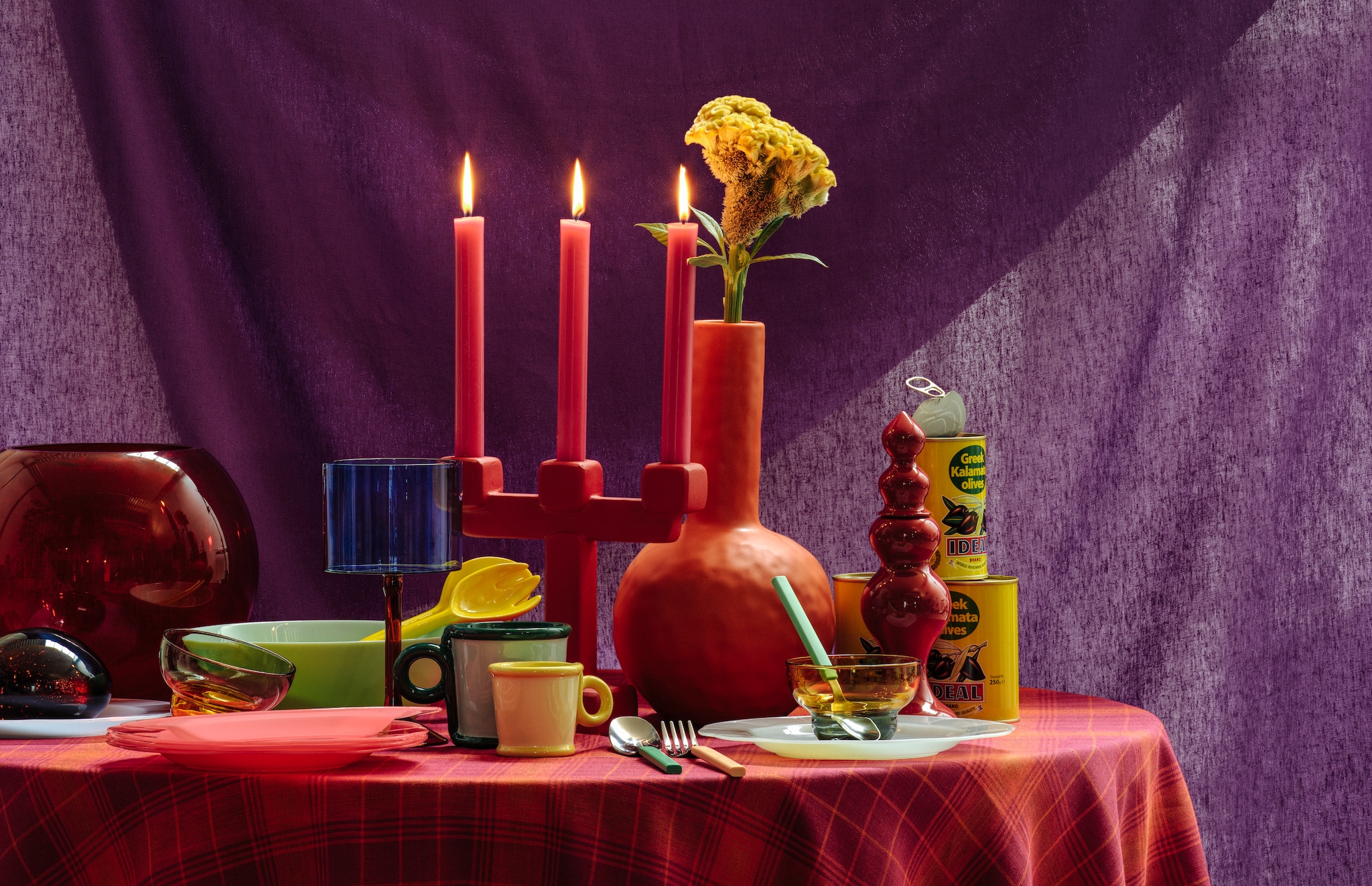 &Klevering kandelaar Chunk L. € 120,-, kop Loop, geel, set van 2 € 25,-, mok Loop, groen, set van 2 € 35,-, slabestek Boavista, keramiek, geel € 32,- (klevering.com). Søstrene Grene kaarsen, roze, set van 10 € 5,-, herbruikbare borden, plastic, gekleurd, set van 4 € 5,-, olijven in blik, greek brilliant kalamata, per stuk € 3,- (sostrenegrene.com). Polspotten Bloated Caps and Jars, glas, 24,6x25 cm (Øxh), set van 4 € 350,-, kopjes Calming Pebbles, small, glas, € 40,-, kopjes Mizu Kiri, glas, groen en geel, set van 2 € 40,-, zout-en-pepermolen, bruin, medium € 80,- (polspotten.nl). Ikea bestek Tangmarla, gekleurd, 16-delig € 20,-, serveerschaal Oftast, glas, groen € 2,- (ikea.com). Urban Nature Culture cocktailglazen Gin-tonic, glas, set van 2 € 50,-, vaas Mae, oranje, 14,8x31 cm (Ø) € 50,- (urbannatureculture.com). Folk and Fiber tafelkleed, Frans linnen, orange picknick € 28,-, doek, Italiaanse linnen, purple sky € 20,- (folkandfiber.nl). Stijlvol wonen 10-2025 | Styling Djamilla van Brussel | Fotografie Benning & Gladkova