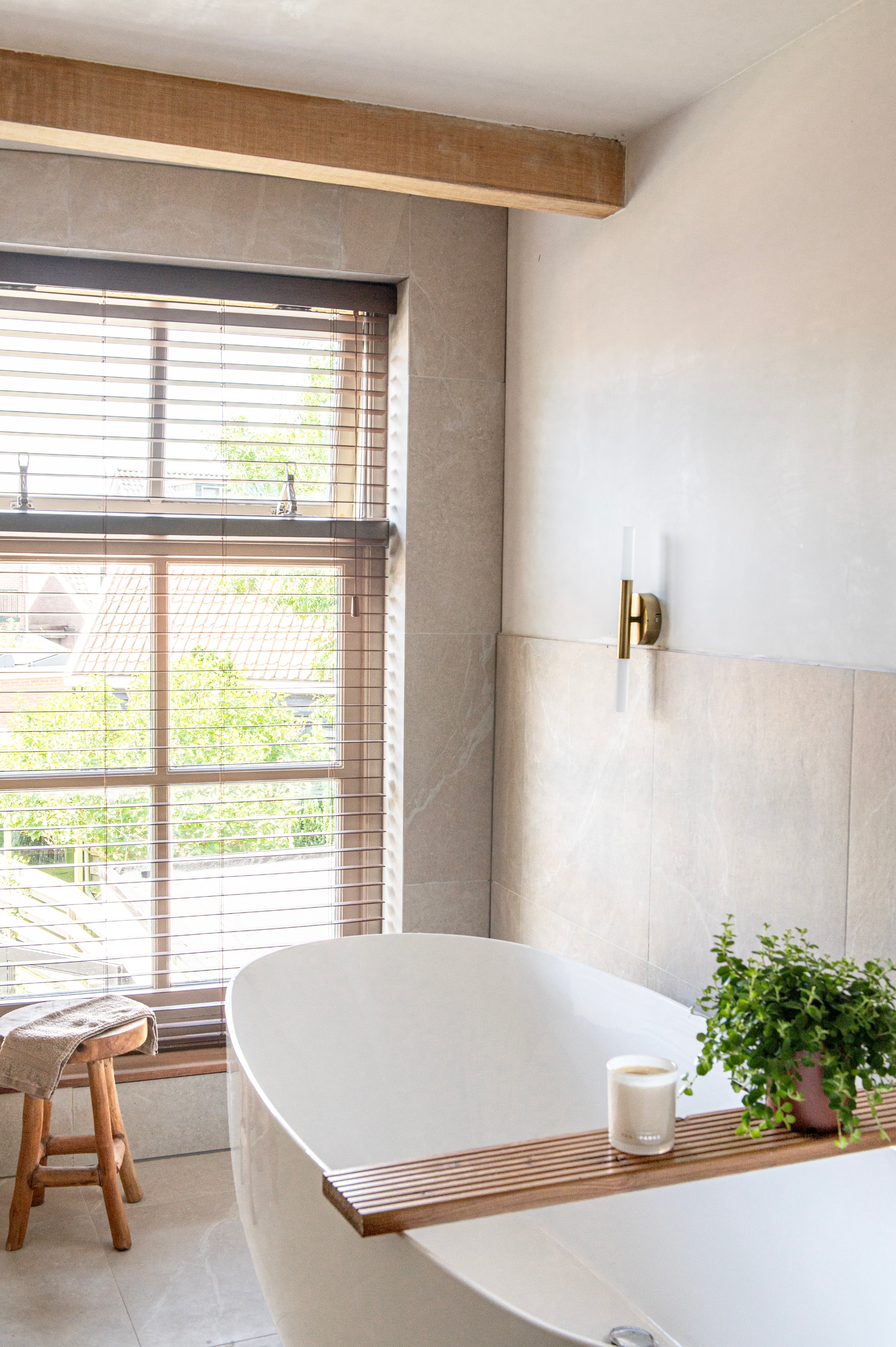 Bad Belaqua van Bernstein Badshop. Plank zelfgemaakt. Geurkaars Ted Sparks. Wandlamp Wanda van Made. Wandtegels Pietra Bo beige mat van Tegels In Huis. vtwonen 12-2025 | styling Jeske Weel | fotografie Caroline Coehorst