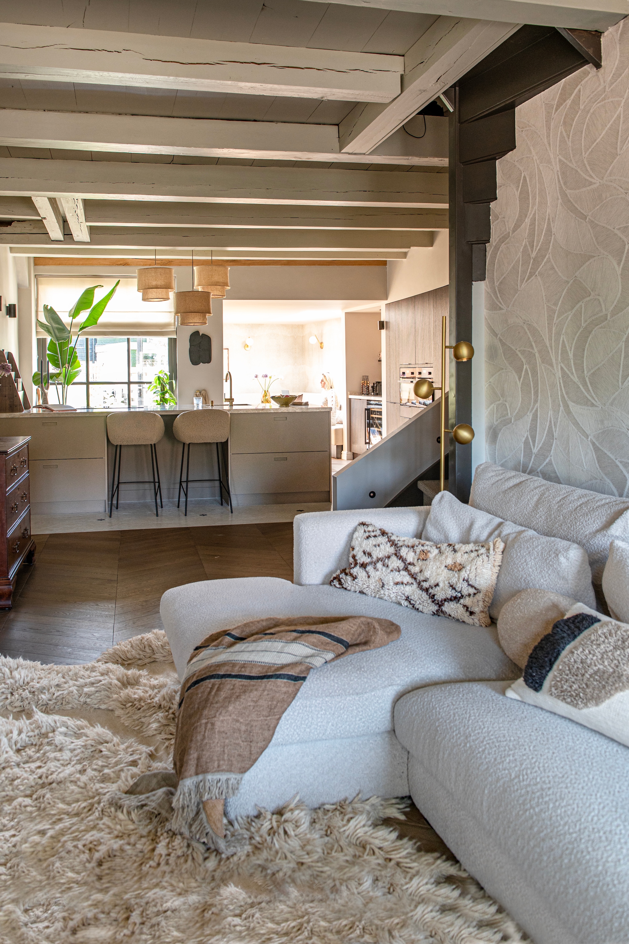 Kussens, plaid, schaal en vloerkleed The James. Keuken Kvik. Mengkraan Caral in geborsteld messing van Wiesbaden. Barkrukken Lova taupe van Giga Meubel. Hanglampen Mariela van Kave Home. vtwonen 12-2025 | styling Jeske Weel | fotografie Caroline Coehorst