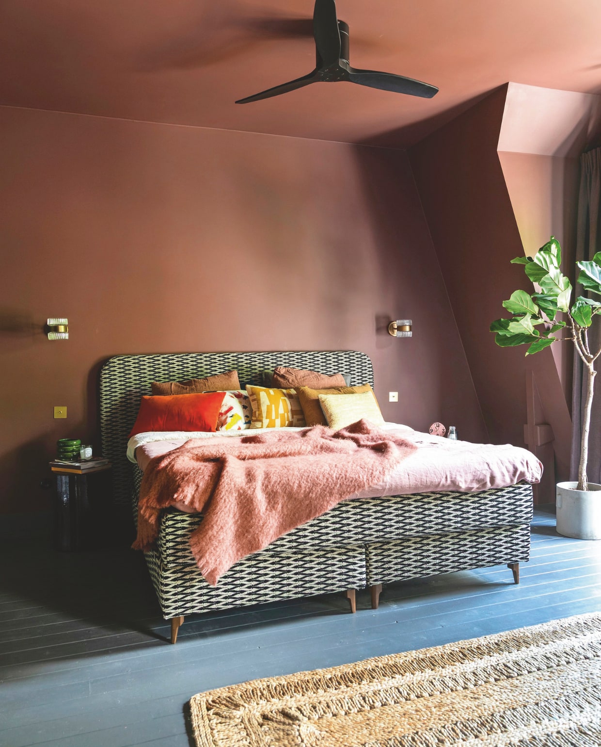 Kleur muur en plafond Full Plum van Flexa Pure, kleur vloer 85% Grafiet van Flexa, rotan vloerkleed HKliving. Bed The Boxspring Club, bedlinnen en plaid By Mölle, kussens van links naar rechts: vintage, Pierre Frey, Dedar, HKliving. Plafondventilator Create, wandlampen Soho Home, messing schakelaars Corston, bloempot Serax. vtwonen binnenkijken 09-2025 | styling en fotografie Theo Bert-Pot, Jelle van de Schoor | tekst Britte Kramer