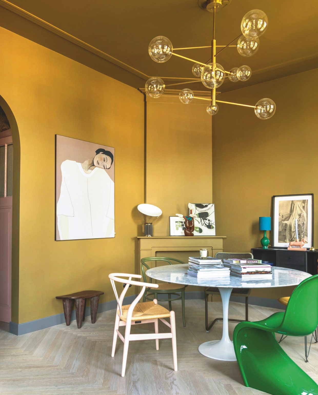 Kleur muren en plafond The Greenhouse 7 van Flexa, houten vloer Vloerenhuis Amsterdam. Eettafel Knoll, stoel links Carl Hansen Pink Limited via Mister Design, groene stoel Vitra. Kunstwerk links Werk aan de Muur, kunstwerk rechts gemaakt door Theo-Berts opa. Tafellamp op schouw Flos. Dressoir Audo, kaarsenhouder teckel Theo-Bert Pot by Karwei. vtwonen binnenkijken 09-2025 | styling en fotografie Theo Bert-Pot, Jelle van de Schoor | tekst Britte Kramer