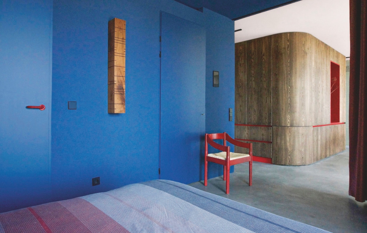 In het slaapgedeelte hebben de muren en het plafond dezelfde tint blauw. Zo wordt de ruimte afgebakend zonder dat een wand nodig is. Het geeft de ruimte bovendien een intieme sfeer. Stijlvol Wonen 8-2025 | Styling & Fotografie Bart Wigger | Tekst Evelien Roels