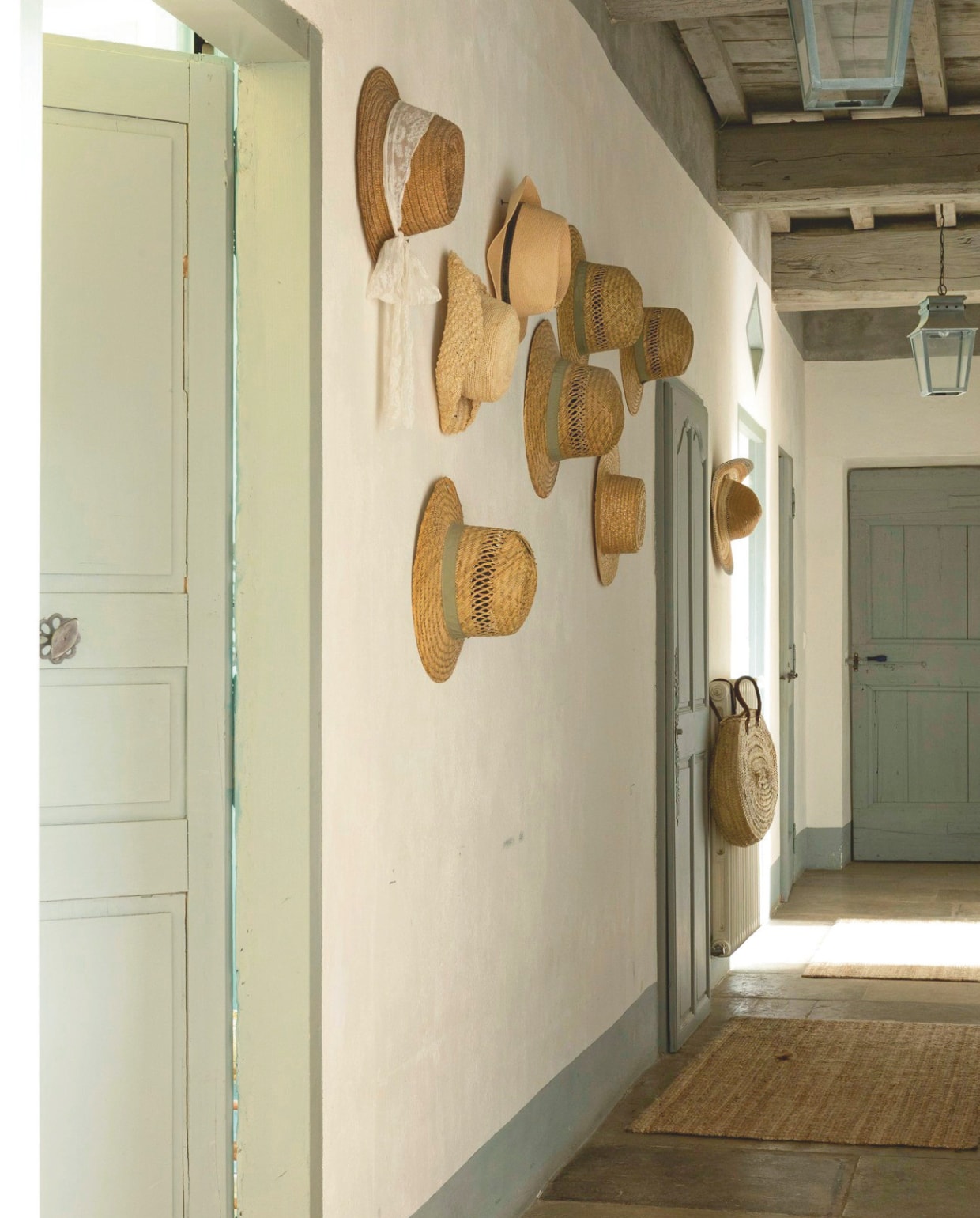De gang naar de slaapkamers, met aan de muur een collectie vintage strohoeden. vtwonen Landelijk 8-2025 | styling Laura Taccari | fotografie Monica Spezia | tekstbewerking Roel Janssen