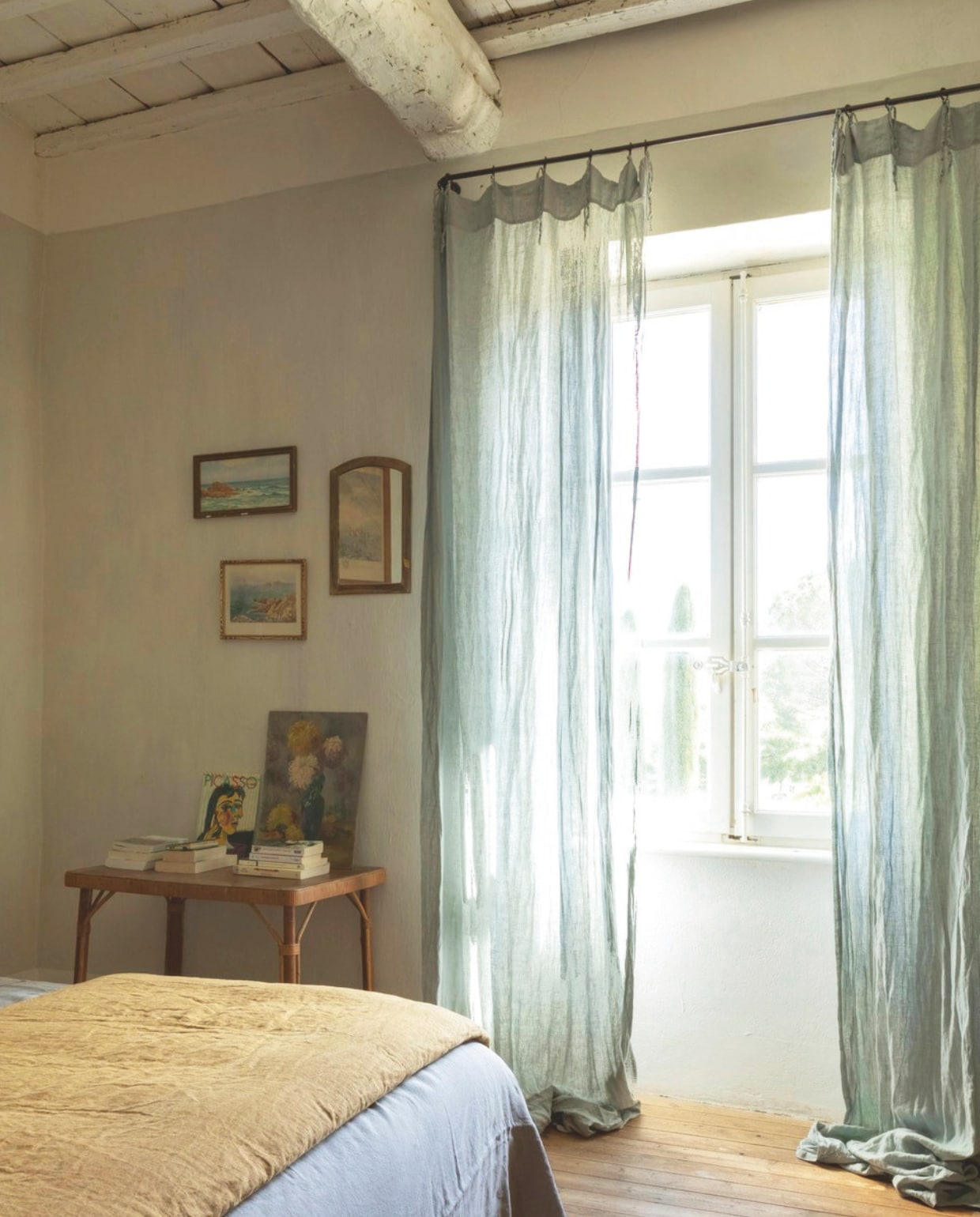 De slaapkamer met panoramabehang Les Papiers van Ninon. Vintage rotan fauteuil. Linnen gordijnen. vtwonen Landelijk 8-2025 | styling Laura Taccari | fotografie Monica Spezia | tekstbewerking Roel Janssen