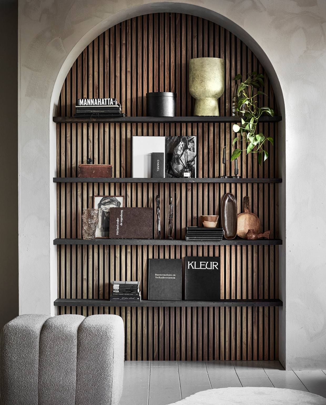 Fsc-gecertificeerde walnoten wandpanelen decor, per stuk 60,5x244 cm (bxh) € 87,82, lakverf Off Black van vtwonen,  1 liter € 46,99, beige grofgeweven poef Erie, 60x50x50 cm (bxdxh) € 159,- (karwei.nl). Steigerhouten planken,  250x20x2,3 cm (lxbxh), per stuk € 17,95 (hornbach.nl). Kalkverf Fresco in Sand Storm, 2,5 liter € 129,94 (pure-original.com). Polyester vloerkleed Wells, 140x240 cm € 90,-, groene glazen kandelaars Avie, vanaf € 5,50, glazen bobbelvaas  € 9,- (kwantum.nl). Saliegroene bloempot van vezelklei Solvi € 27,50 (jysk.nl). Oude foto en kunstboeken, vanaf € 2,50, houten kistje € 0,50, houten tribalfiguren, per stuk € 6,95, bruin aardewerken schaaltje € 1,50, broodplank met handvat € 0,50, houten pot met oor € 0,50 (kringloopwinkel). Geurstokjes € 15,99, keramieken ovale serveerschaal € 18,99 (hm.com). Notenhout lijst, 20x30 cm € 15,- (hema.nl). Overig privébezit.  vtwonen 01-2024 | styling Marit Saladini | fotografie Peggy Janssen | assistentie Kiki de Koning, Willow Poyner, Rosa van Schie