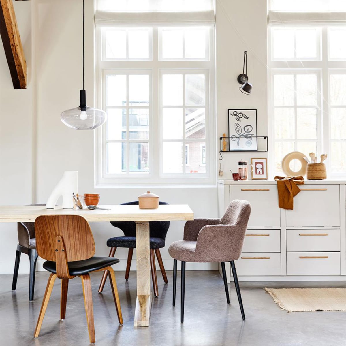 Mangohouten eettafel Deck in kleur Naturel, 200x90x78 cm (lxbxh) € 899,-, ook verkrijgbaar als ronde variant in kleur Clay, 120×78 cm ( Øxh) € 749,-. Linksachter: eetkamerstoel Scroll, met warmgrijze geweven stof, 53x50x76 cm (bxdxh) € 299,-. Rechtsachter: zwarte eetkamerstoel Cape, gemêleerde stof en hout, ook verkrijgbaar in blauw, 55x65x77 cm (bxdxh) € 199,-. Aan het hoofd: taupe eetkamerstoel Dining van geweven teddystof en metaal, ook verkrijgbaar in off white, 62x53x83 cm (bxdxh) € 249,-. Voor de tafel: walnoothouten eetkamerstoel Classic met PU lederen zitting, 48x50x81 cm (bxdxh) € 149,-. | m.m.v. vtwonen.nl (hanglamp Alton 35 van Nordlux, object op tafel van vtwonen, kommen op tafel HKliving, koperen perculator Leopold Vienna, terrakleurige kop HKliving, artwork Hôtel Magique), hm.com (vloerkleed). Overig privébezit. vtwonen 02-2022 | productie Tanja Saarberg | styling Marlies Does | fotografie Bart Brussee