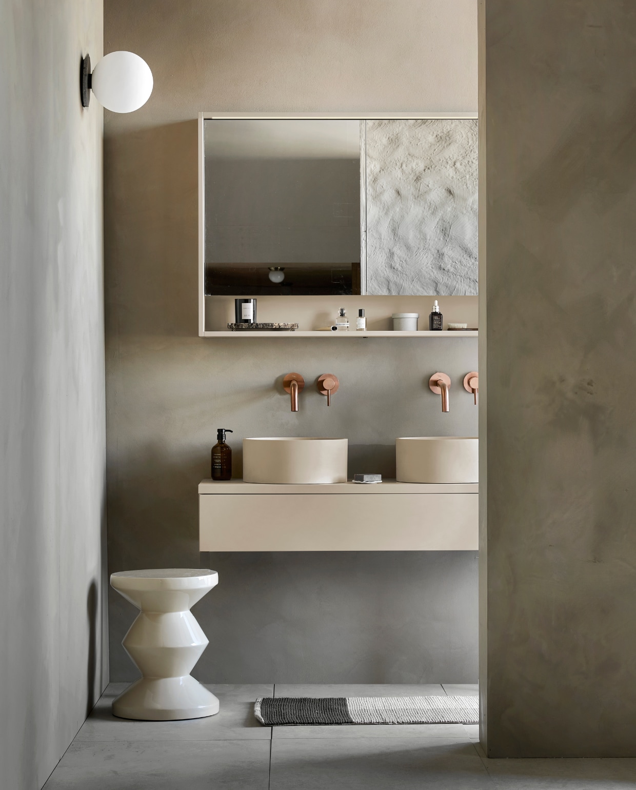 Kunststof spiegel Gorgeous in zand, inclusief ledstrip met bewegingssensor, 59,6x120x10 cm (lxbxd) € 500,- (ook verkrijgbaar in breedtematen 60 cm en 90 cm en in wit, grijs en zwart). Top Solid wastafel Wide in zand, 40x121x20 cm (lxbxd) € 870,- (ook verkrijgbaar in breedtematen 61 cm en 91 cm, in wit en in Quartz en Marmer). Kunststof afdekblad in mat zand, 120 cm € 240,-. Kunststof onderkast Tidy in zand, 1 lade met handgreep, 20x120x40 cm (lxbxd) € 737,- (ook verkrijgbaar in breedtematen 60 cm en 90 cm en in wit, grijs en zwart). Top Solid bad Endless in zand, 160x73x57 cm (lxbxd), inhoud 200 liter € 3450,- (ook verkrijgbaar in Quartz, grijs en zwart). Op vloer tegels Raw Sand van vtwonen, 60×120 cm, per m² € 74,-.  M.m.v. vestingh.nl (kleur op de muur Brown Wood No. 222), vtwonen.nl (wandlamp TR Bulb van Menu, kruk Chubby van  Pols Potten), nordal.eu (rond marmeren plateau), zarahome.com (geurkaars in glas, zeeppompjes, zeepschaaltje, handdoek), stories.com (parfum), desco.be (kranen). Overig privébezit.