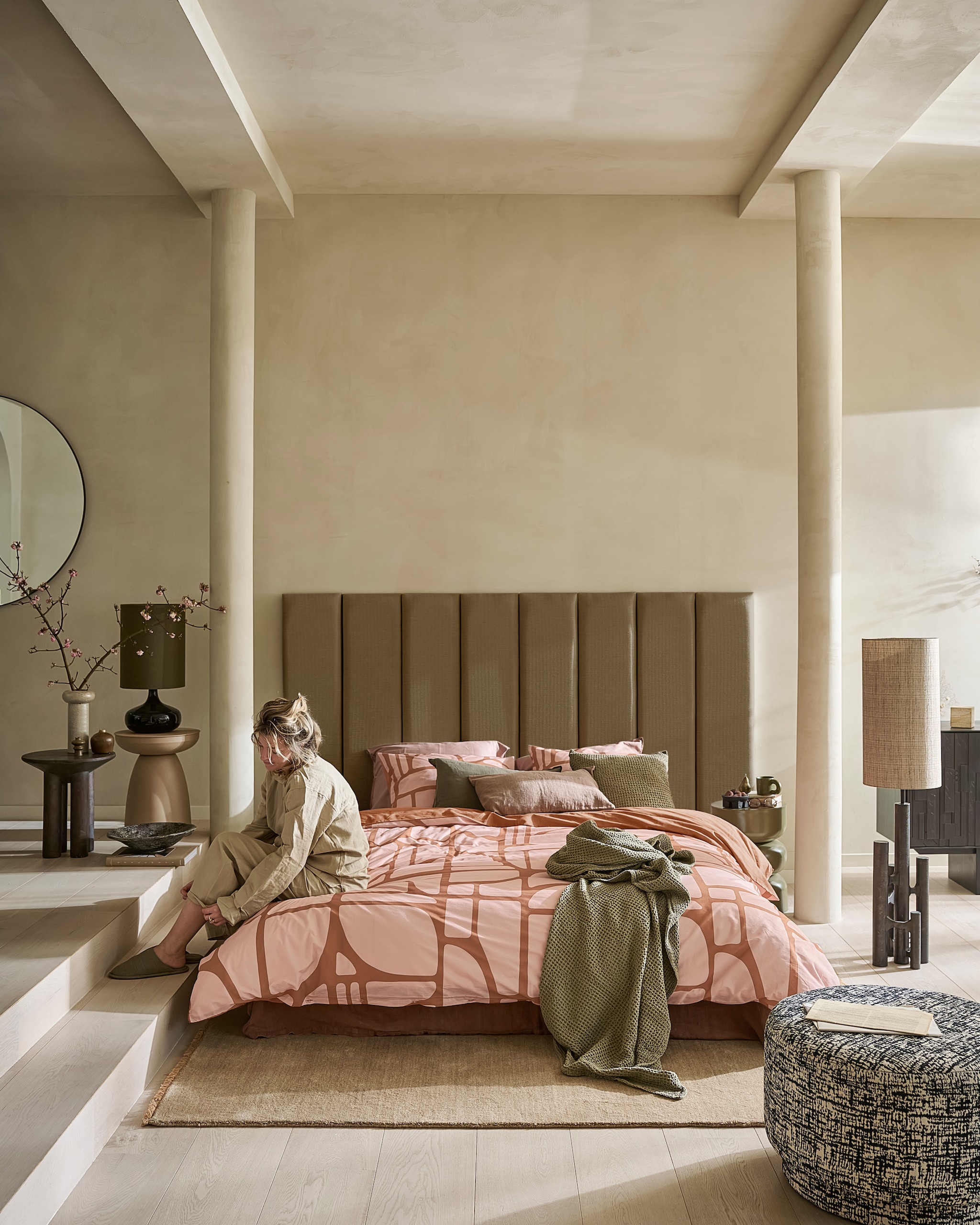 vtwonen dekbedovertrek Bold Shapes, katoen, zachtroze, vanaf € 49,95.M.m.v. urbannatureculture.com (tafellamp), versmissen.nl (vloerlamp met kap, donkerbruine bijzettafel), loods5.nl (vloerkleed, plaid, vaas, groene bijzettafel, lichtroze bijzettafel, schaal), bolia.com (nachtkleding), nordal.com (poef, mok), head-boards.nl (hoofdbord), zarahome.com (vaasjes, sierkussens, zwart schaaltje met lavastenen), designtales.nl (decoratieve peer). Overig privébezit. vtwonen 12-2025 | styling Kim van Rossenberg | fotografie Sjoerd Eickmans
