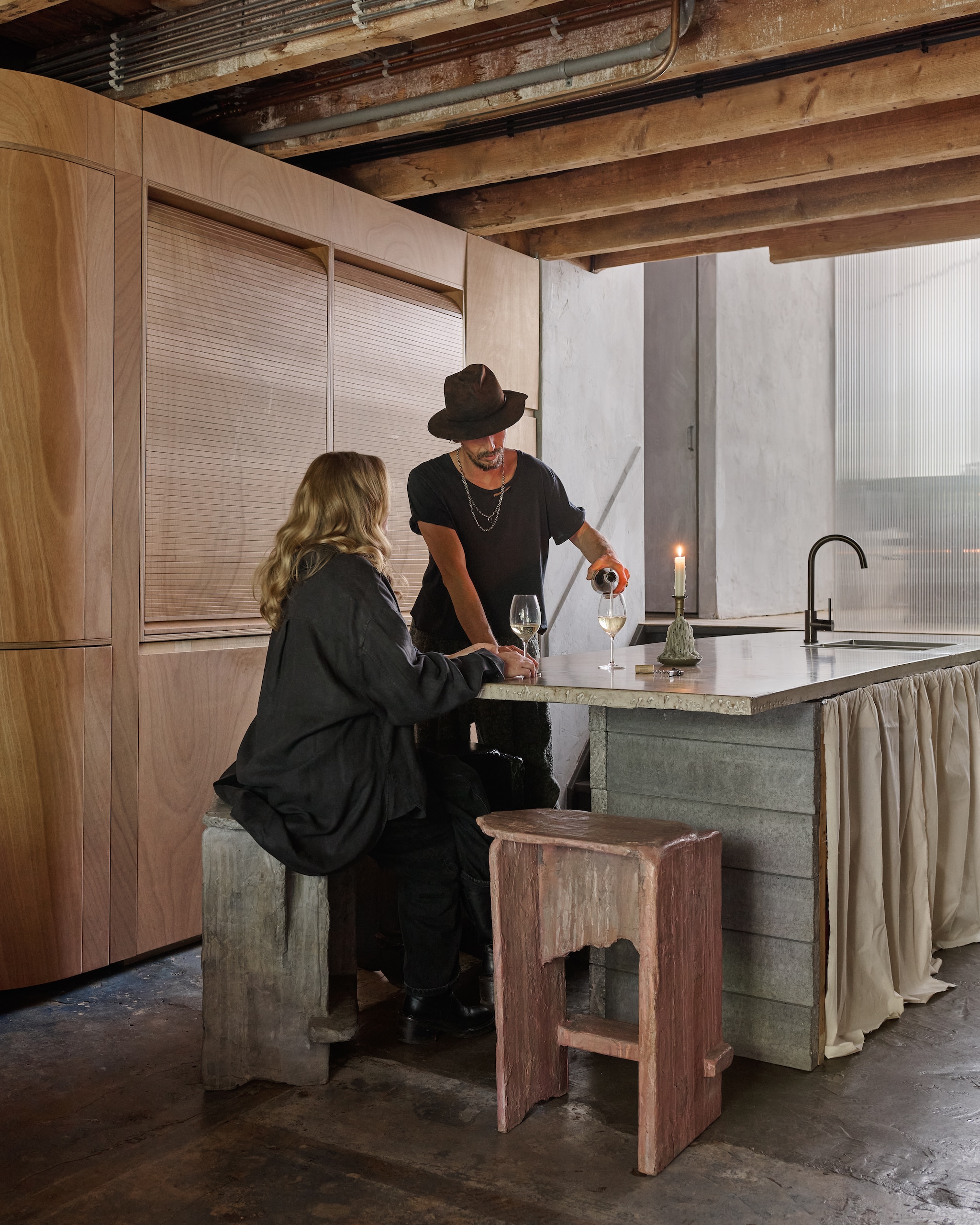 Keuken van betonblokken, afgewerkt met een betonmix en groene zeep, kastenwand in Okoumé-hout. Krukken van hout, afgewerkt met een mix van zand, klei, kunsthars en kleurpigment. Gordijnen onbewerkt katoen. Alles eigen ontwerp. stijlvol wonen 10-2025 | styling Tamara Botter | fotografie Kasia Gatkowska