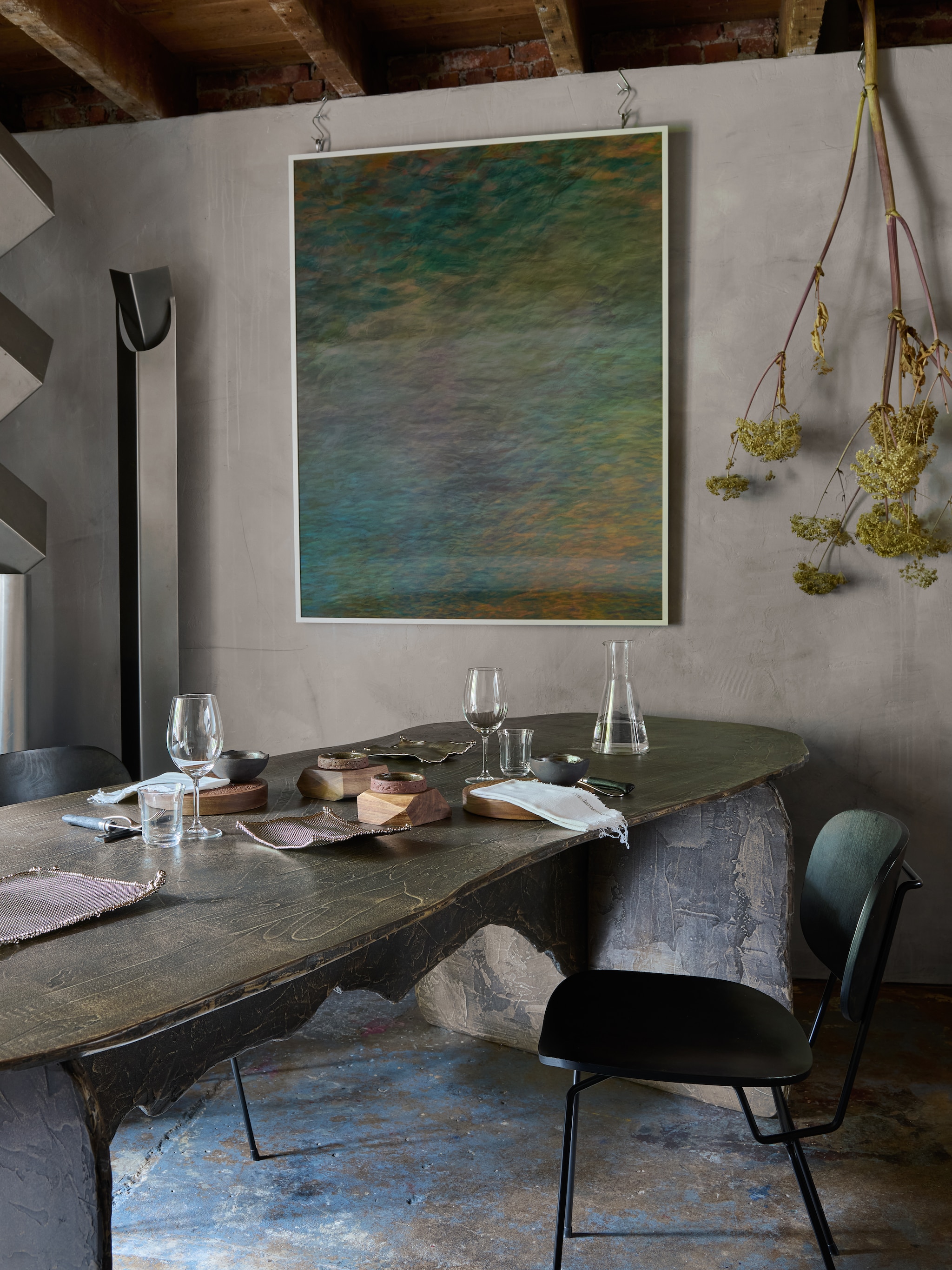 Lichtobject Frank Penders. Tafel Bastiaan Kalmeyer voor Fundamental Objects. Stoel Lensvelt. Metalen tableware Odd Matter. Overig servies Merging Matter. Kunstwerk aan de muur Pim Top. Schenkkan is laboratoriumglaswerk. stijlvol wonen 10-2025 | styling Tamara Botter | fotografie Kasia Gatkowska