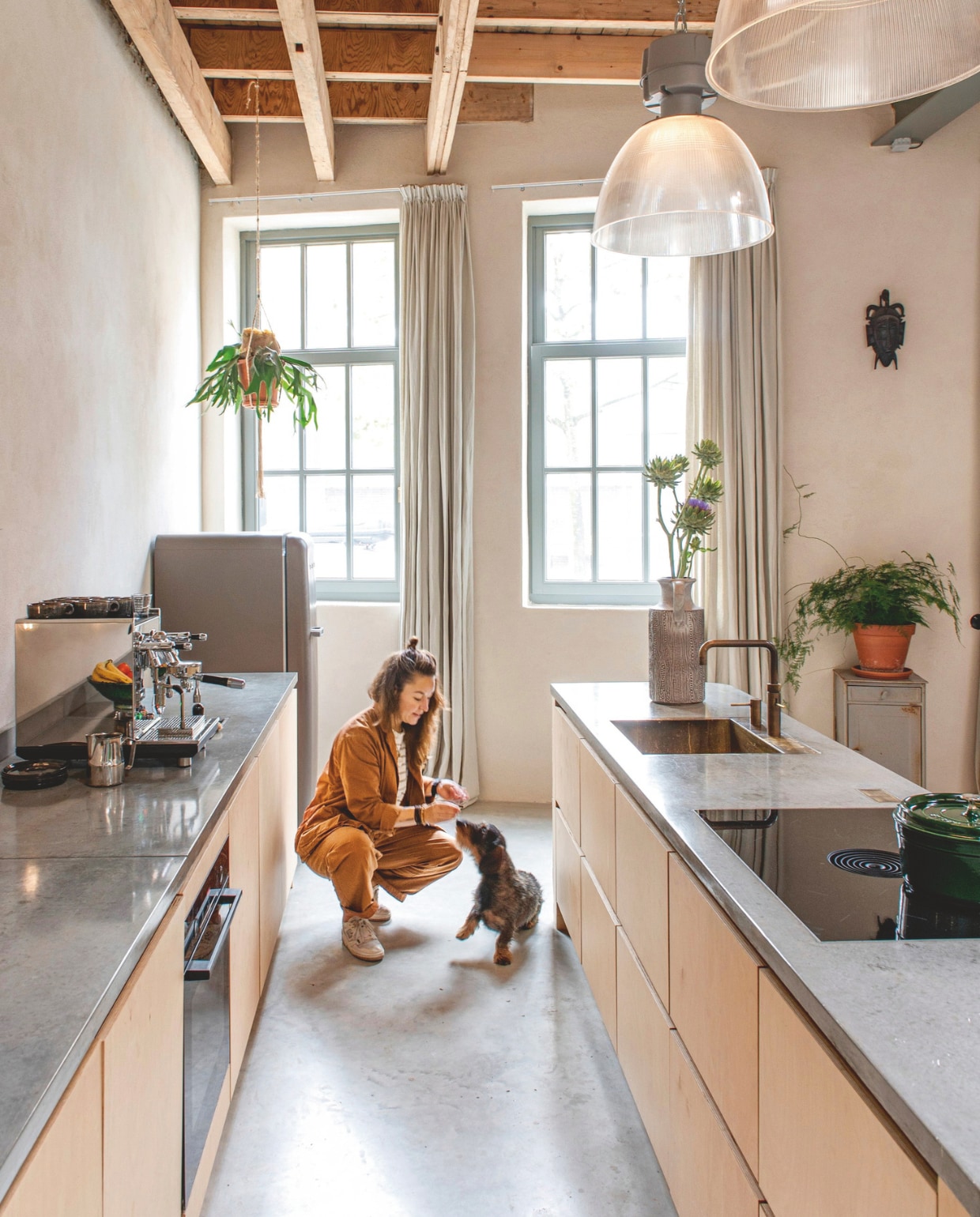 Keuken ontworpen door Fleur en gebouwd door Pand B, aanrechtblad, koperen wasbak en kraan Pronck, kookplaat Bora, oven Bosch, koelkast Smeg, koffiemachine en bonenmaler ECM. Pan Staub, kop-en-schotels Sergio Herman. Lampen, grijze vaas, industrieel kastje en Afrikaans masker vintage vondsten. Leemstuc Tierrafino, vloer gevlinderd beton via Denzo Bouw.