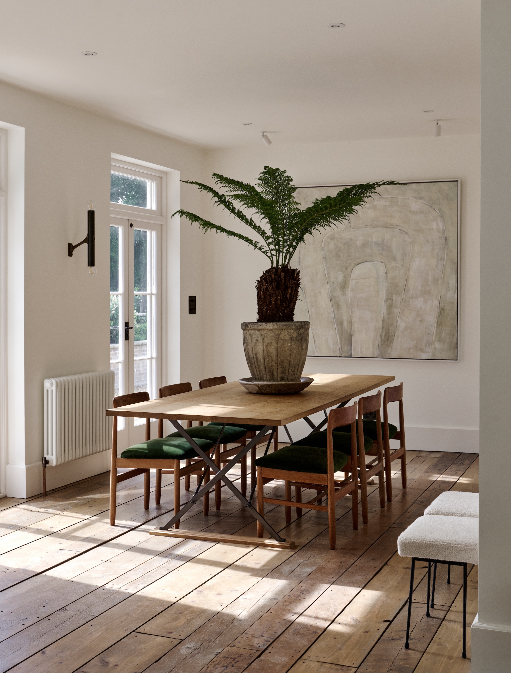 Eettafel Rose Uniacke. Stoelen van Davina’s ouders, bekleed met groen katoenfluweel van Rose Uniacke. Krukjes Parijse vlooienmarkt, bekleed met bouclé van Pierre Frey. Wandlamp Matthew Cox. Kunstwerk Davina Stanley. vtwonen 12-2025 | productie Living Inside | styling Ali Heath | fotografie Brent Darby