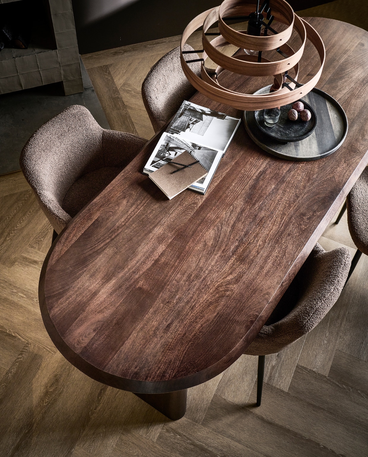 Walnootfineer eettafel Ellips, 180x90x75 cm (lxbxh) € 1299,-, ook in 240x90x75 cm (lxbxh), eetkamerstoelen Dining in taupe, teddystof en metaal, 62x53x81 cm (bxdxh) € 249,-, ook in teddystof off white. M.m.v. vtwonen.nl/shop (notenhouten hanglamp van ETH, schilderij van Kave Home, houten pepermolen van Ferm Living, mangohouten bord van vtwonen, vloerkleed van Bolia), hm.com (zwart houten dienblad), karwei.nl (muurverf Warmbruin van vtwonen, gordijn Drizzle in off white van vtwonen), vtwonen.nl (pvc-vloer Herringbone in Sun Kissed van vtwonen). Overig privébezit.  vtwonen 05-2023 | productie Tanja Saarberg | styling Sanne Ketelaar | fotografie Sjoerd Eickmans