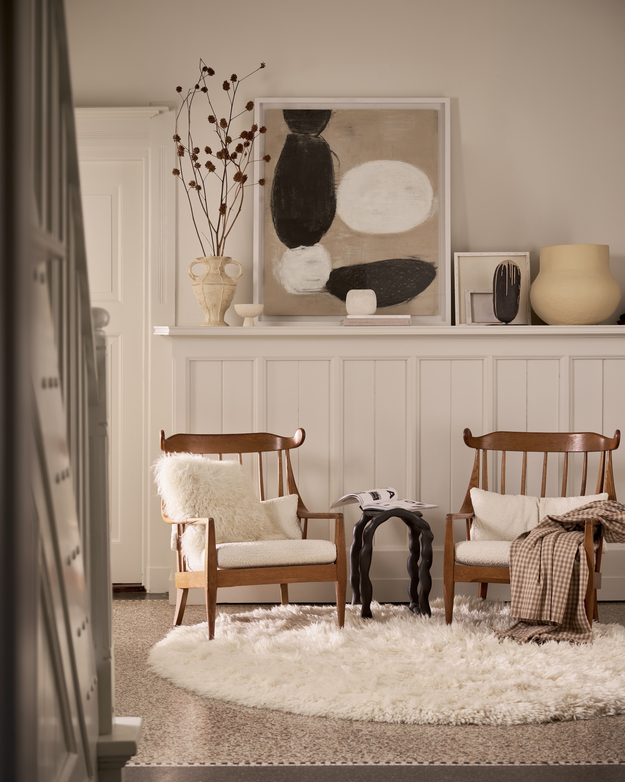 Momo Rugs vloerkleed Snow white, wol en katoen, wit, 200 cm (Ø) € 1695,- (vloerkledenwinkel.nl). Best Wel Hip Cowhorn midcentury fauteuils, hout bekleed met bouclé wol, bruin en wit, set van 2 € 3790,- (bestwelhip.nl). Ferm Living bijzettafel Rotben, zwart, metaal, 45x32x54 cm (bxdxh) € 424,-(fermliving.com). Urban Nature Culture pot Frida, katoen-maché € 219,99, schaaltje Bolle op voet € 17,99 (shop.vtwonen.nl). Vachtenspecialist kussen Tibet, lamsvacht, offwhite, 45x45 cm (lxb) € 64,95 (vachtenspecialist.nl). Zara Home geruite deken, beige-bruin, 240x220 cm (lxb) € 59,99 (zarahome.com). Mette Sophie object Caillou, keramiek, prijs op aanvraag (mettesophie.com). HKliving vaas New Classics, keramiek, cream € 79,95, ingelijst kunstwerk Offset, zwart-wit, 102x102 cm (lxb) € 495,- (hkliving.com). Overig privébezit. vtwonen 12-2025 | styling Cleo Scheulderman | fotografie Jeroen van der Spek