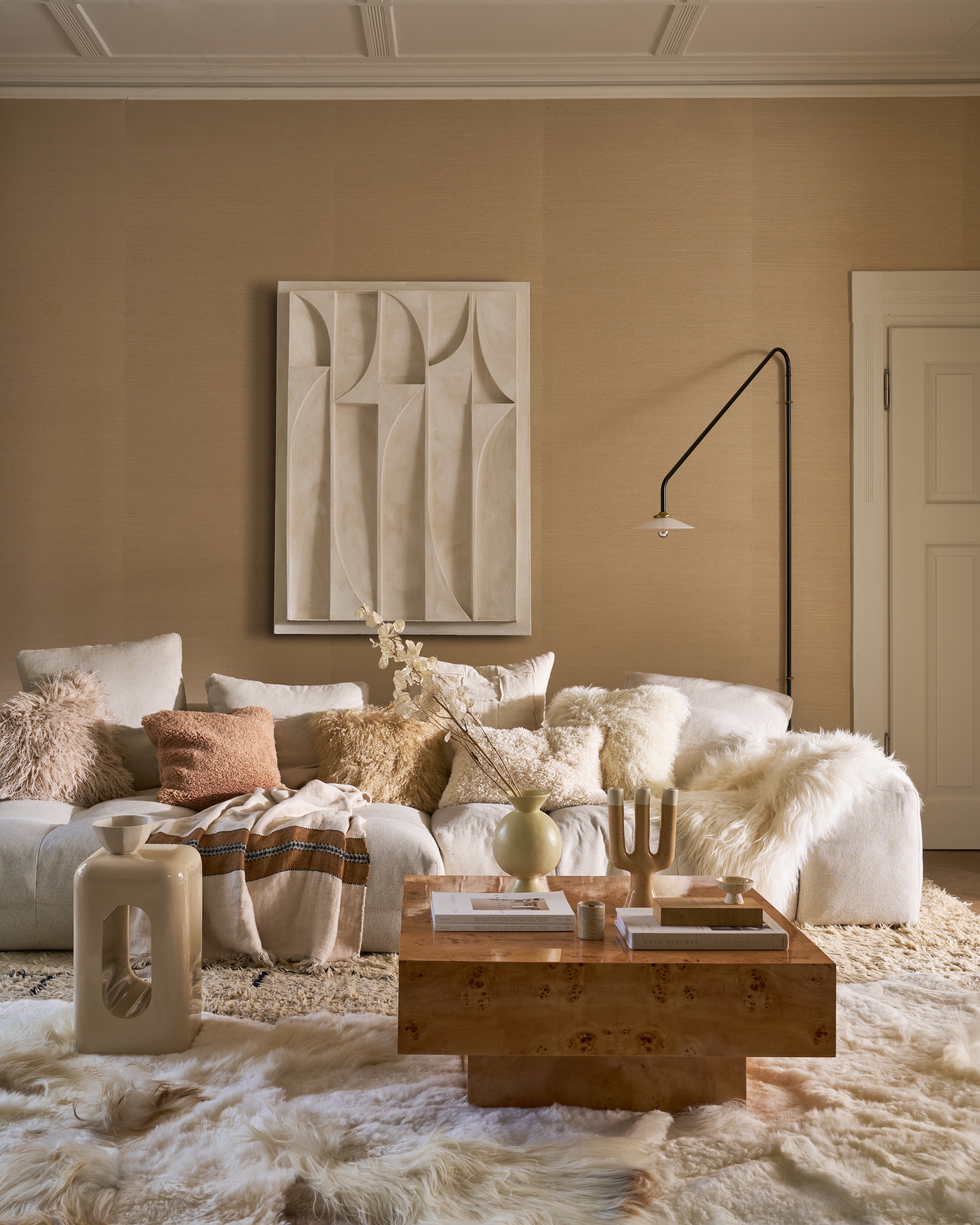 Art in Return kunstwerk, offwhite, 140x100 cm (lxb), prijs op aanvraag (artinreturn.nl). Dutchbone salontafel Quinn, wortelhoutfineer met glanzende lak, 90x90x39 cm (lxbxh) € 695,- (dutchbone.com). Zuiver bijzettafel Creek, kunststof, beige hoogglans, 29x29x48 cm (lxbxh) (zuiver.com). Urban Nature Culture vaas Kudos, keramiek € 49,99, kandelaar Nox, keramiek, beige € 49,99, kommetje Lav op voet, keramiek, beige € 9,99 (shop.vtwonen.nl). Vachtenspecialist schapenvacht vloerkleden, melange wit, 180x120 cm (lxb) € 695,-, kussen Tibet, lamsvacht, offwhite en camel, 45x45 cm (lxb) € 64,95, schapenvacht IJslands, op bank, wit € 79,95 (vachtenspecialist.nl). Saba Italia bank Pixel, 296x136x65 cm (lxbxh), prijs op aanvraag (kasstoor.nl). Valerie Objects wandlamp nr 4, door Muller Van Severen, metaal en glas, zwart, 180x90 cm (lxb) € 880,- (mudinmay.nl). Libeco deken Highland Stripe, linnen, beige-bruin, 140x220 cm (lxb) € 336,- (sukha.nl). Zara Home kussenhoes, teddy crème, 60x40 cm (lxb) € 25,99, kom, keramiek, zand € 9,99 (zarahome.com). H&m Home kussenhoes Teddy, lichtbruin, 50x50 cm (lxb) € 19,99, kussenhoes Fluffy, beige € 24,99 (hm.com). Phillip Jeffries behang Manila Hemp 9820, kleur plaster, 91,4x732 cm (bxl) per rol, prijs op aanvraag (phillipjeffries.com). vtwonen 12-2025 | styling Cleo Scheulderman | fotografie Jeroen van der Spek